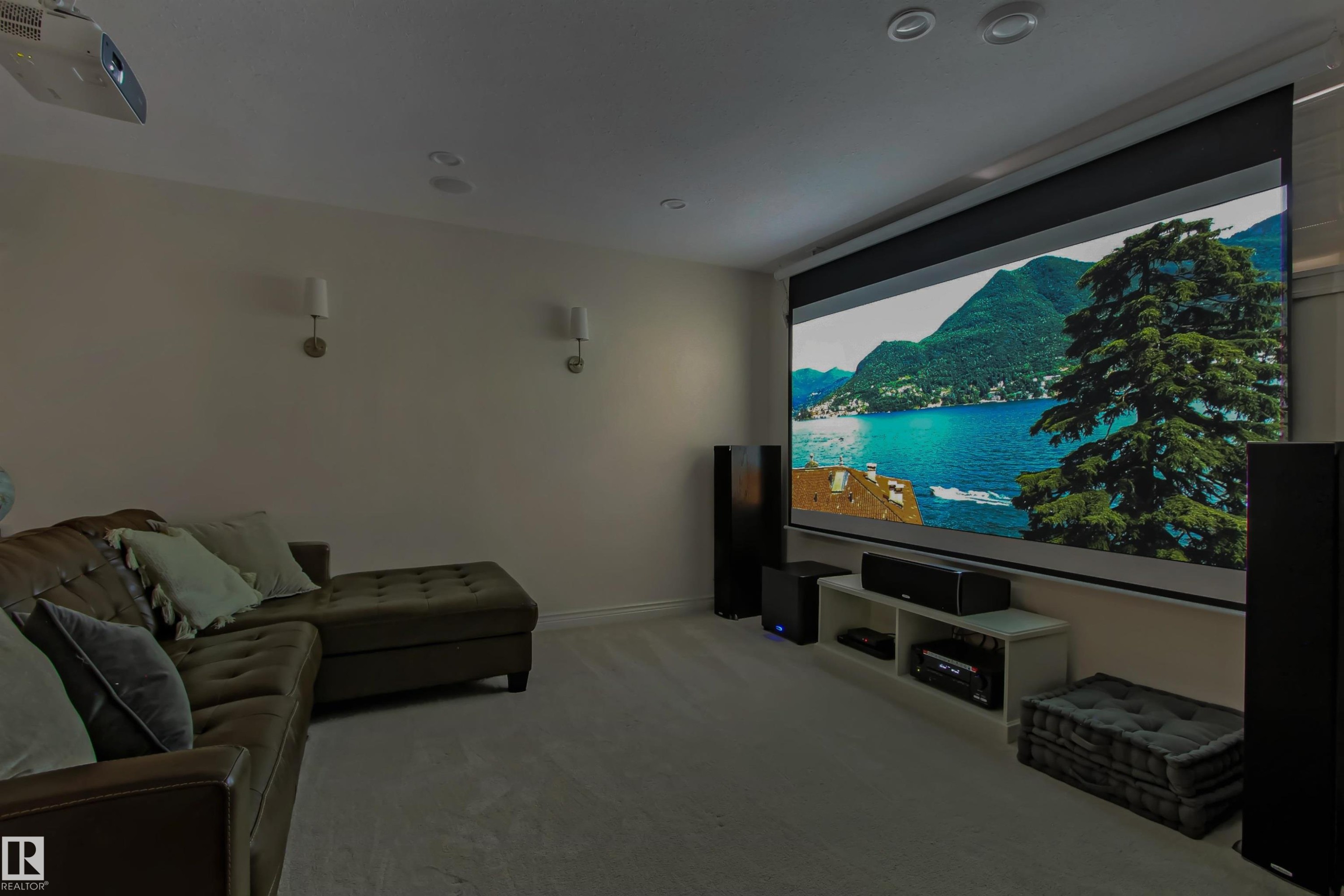 Dedicated media room featuring a large projection screen, ceiling-mounted projector, wall sconces, recessed lighting, and carpeted flooring - 34 Falcon Road, Cold Lake, AB