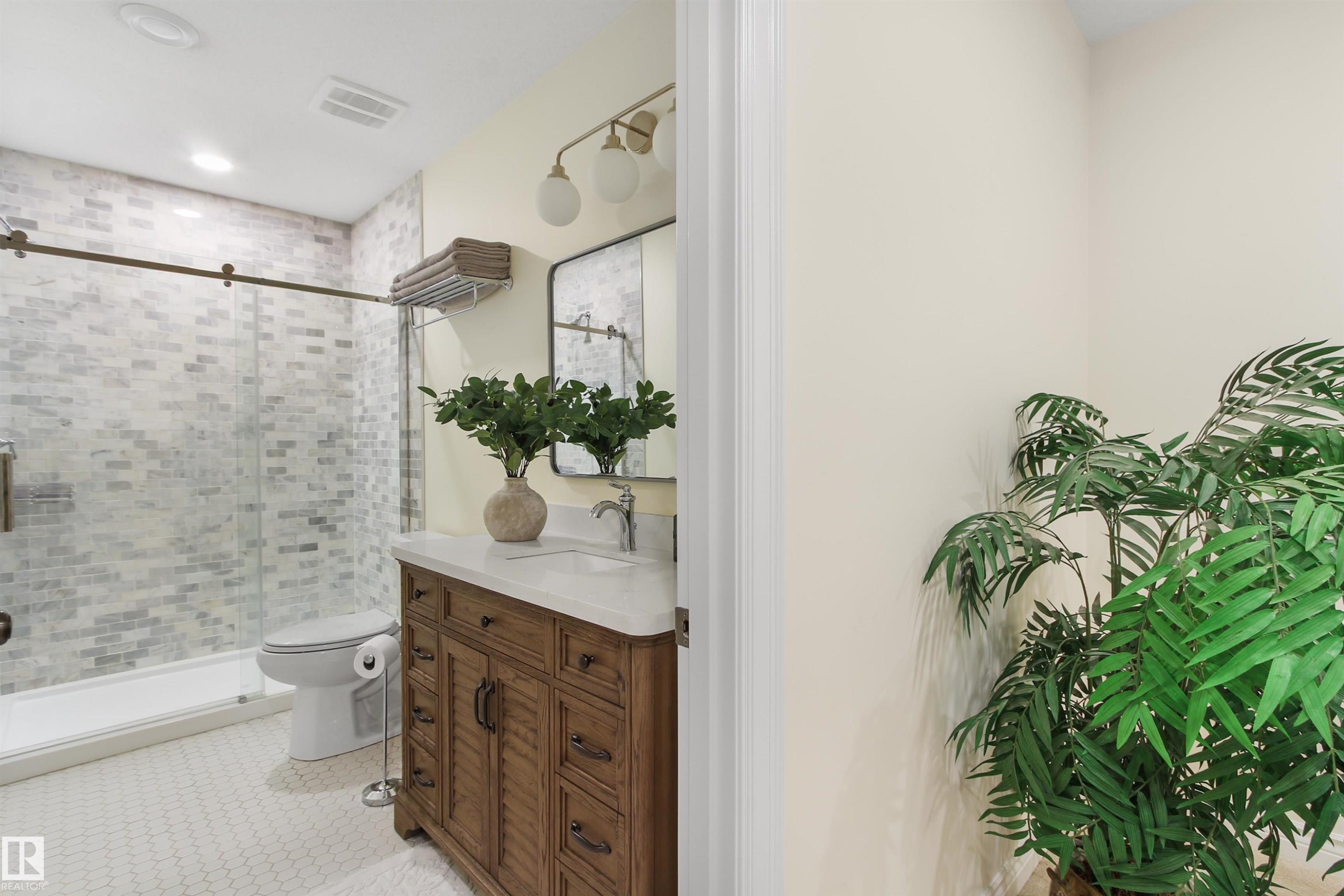Bathroom featuring a wood-finish vanity with a white countertop, a rectangular mirror, and a wall-mounted light fixture - 34 Falcon Road, Cold Lake, AB