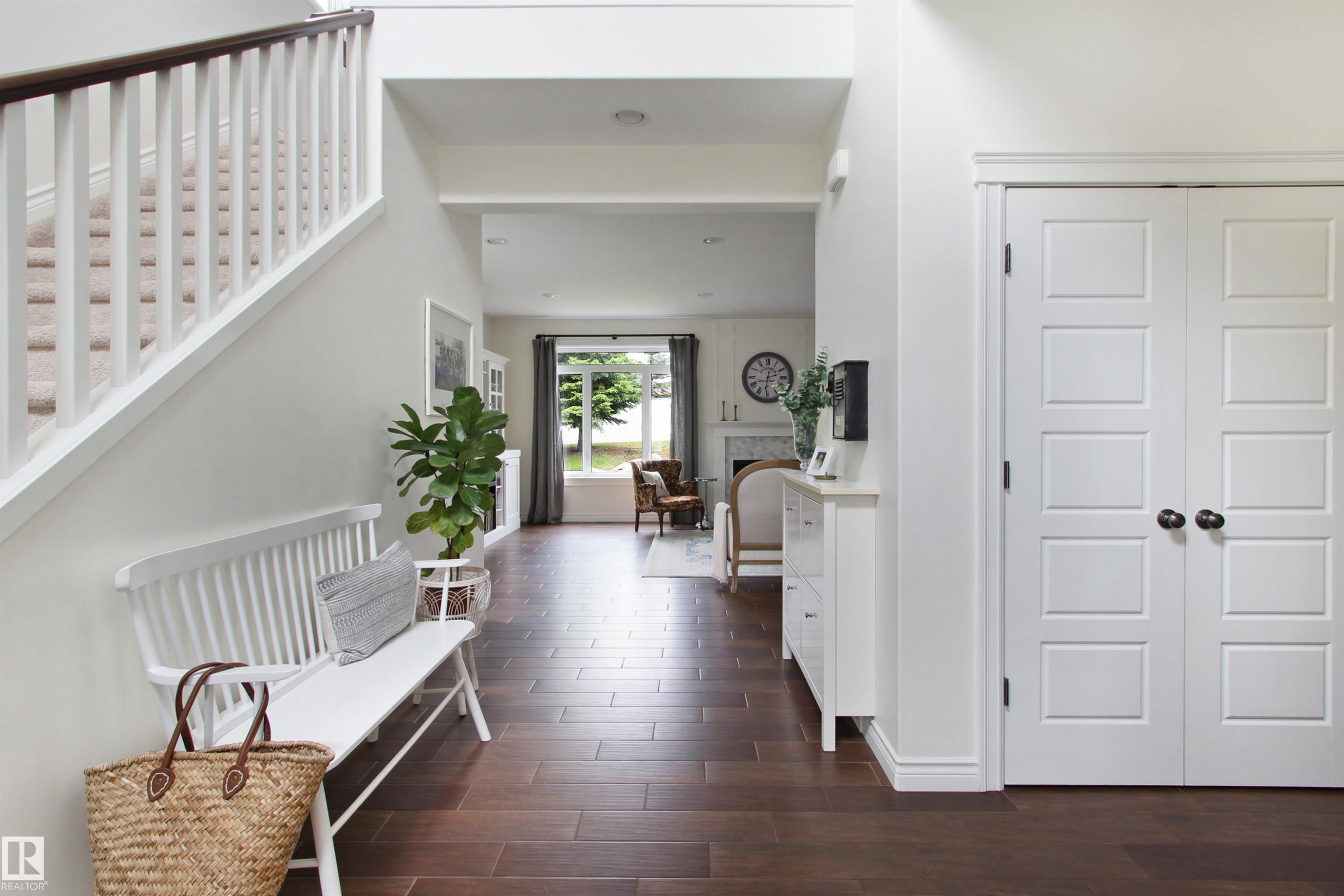Foyer featuring wood-finish flooring, a white staircase with a dark wood handrail, and white paneled doors - 34 Falcon Road, Cold Lake, AB