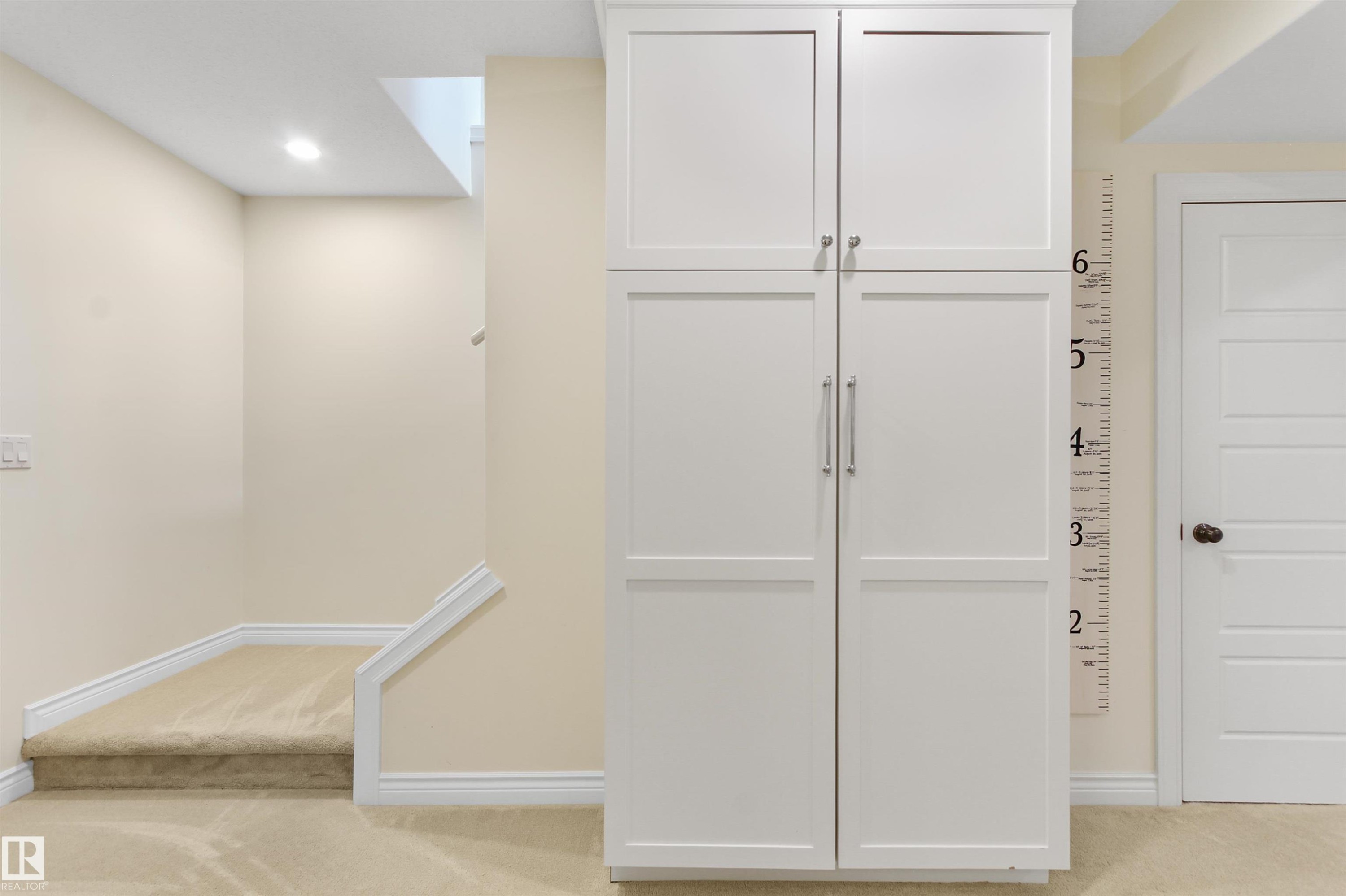 Built-in white cabinetry with brushed nickel hardware, neutral-toned walls, recessed lighting, carpeted staircase, and white trim throughout - 34 Falcon Road, Cold Lake, AB