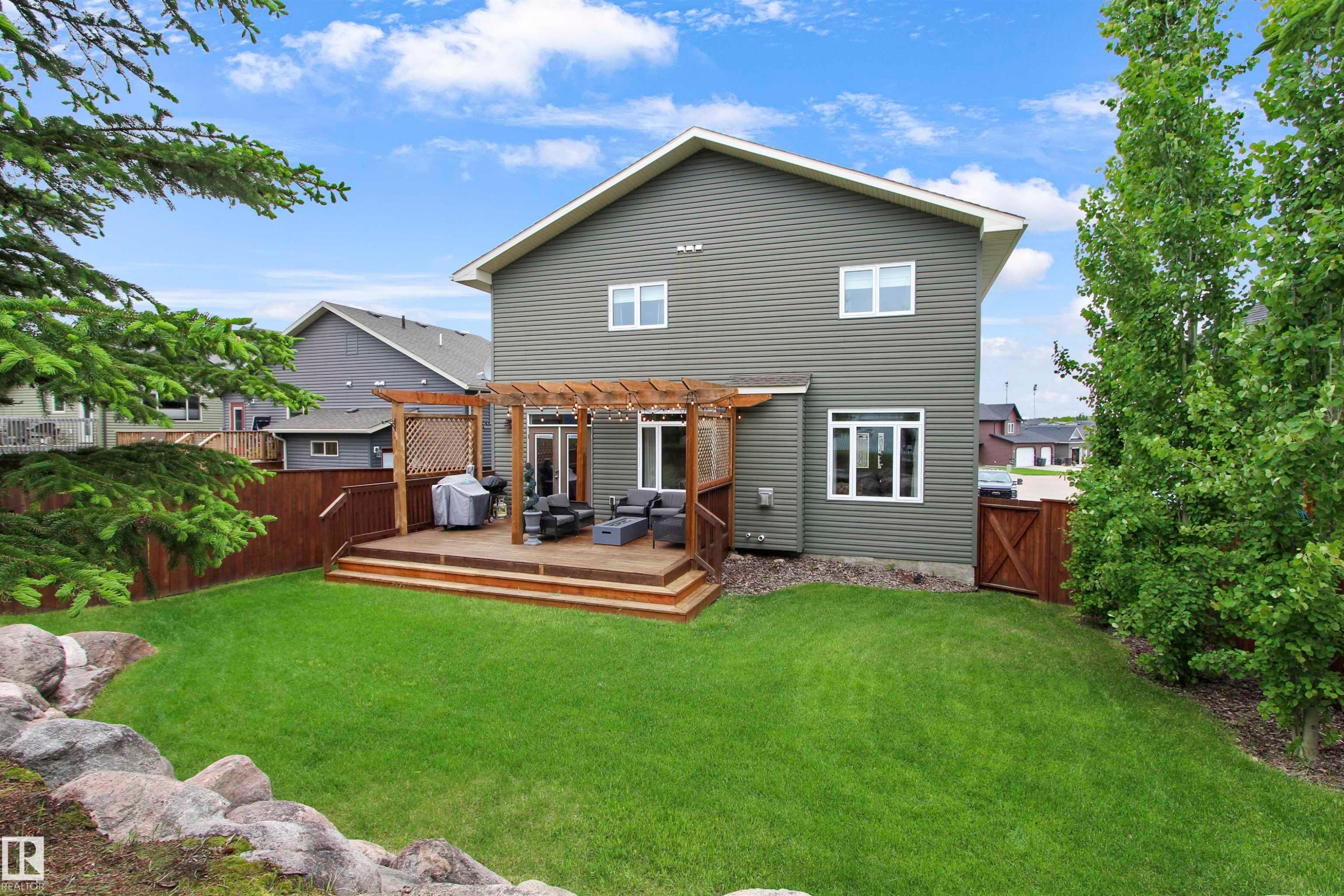 Expansive backyard with a multi-level wood deck, pergola, and decorative rock landscaping - 34 Falcon Road, Cold Lake, AB
