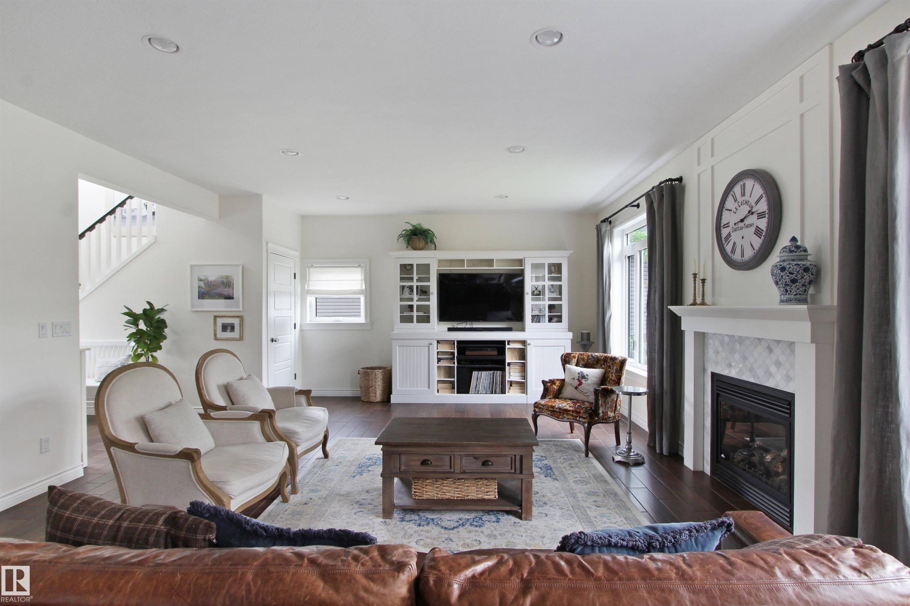 Spacious living area featuring dark wood-finish flooring, a built-in media center with integrated shelving, and a white mantel fireplace with a patterned tile surround - 34 Falcon Road, Cold Lake, AB
