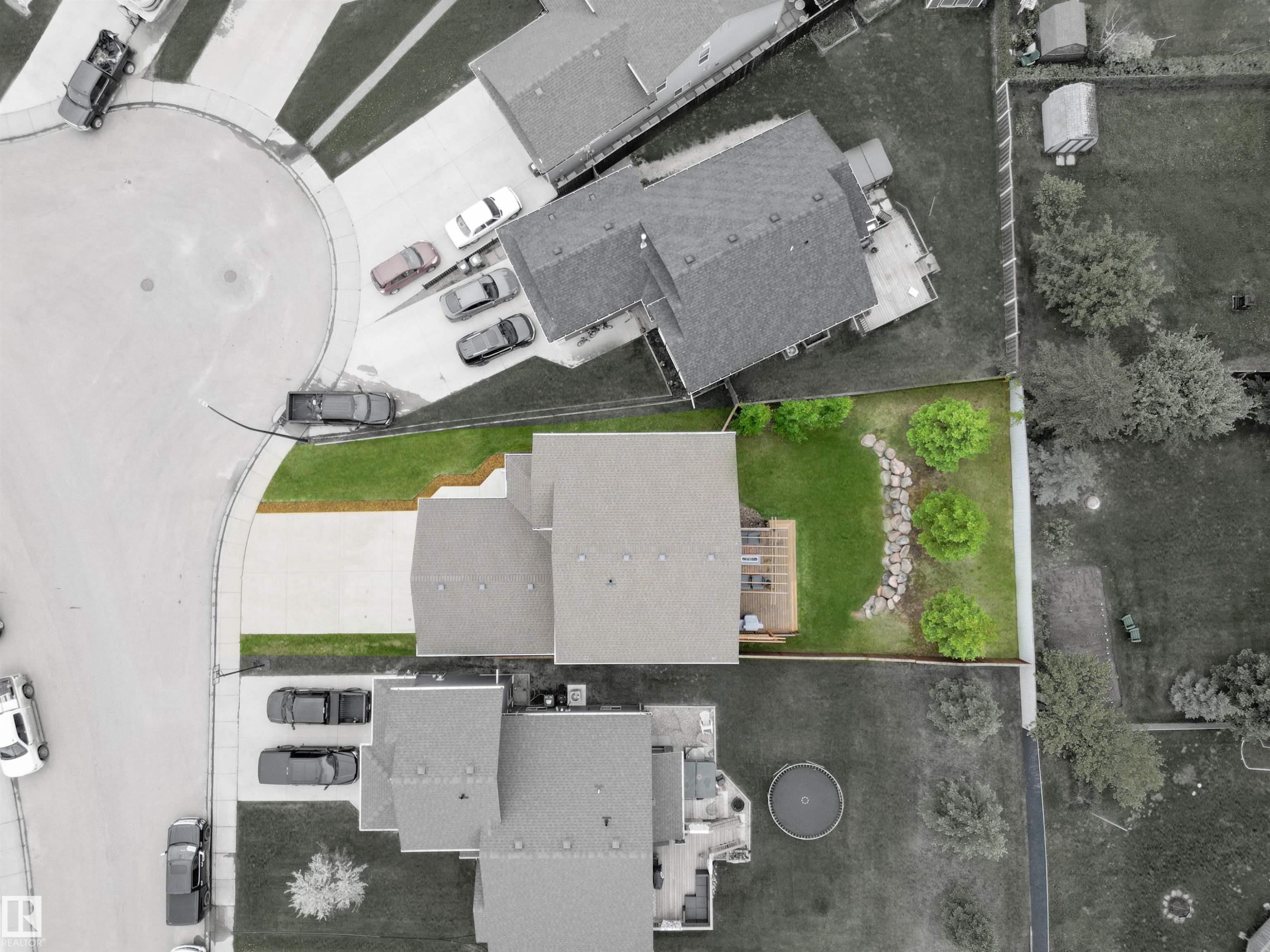 Expansive backyard featuring a green lawn, wood deck, and a rock garden with plantings - 34 Falcon Road, Cold Lake, AB