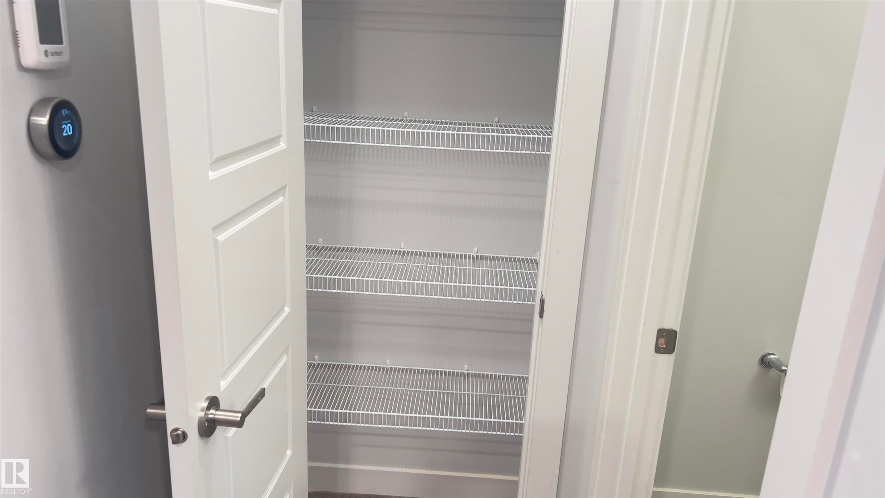 White pantry door with brushed nickel hardware revealing wire shelving - 90 804 Welsh Drive, Edmonton, AB