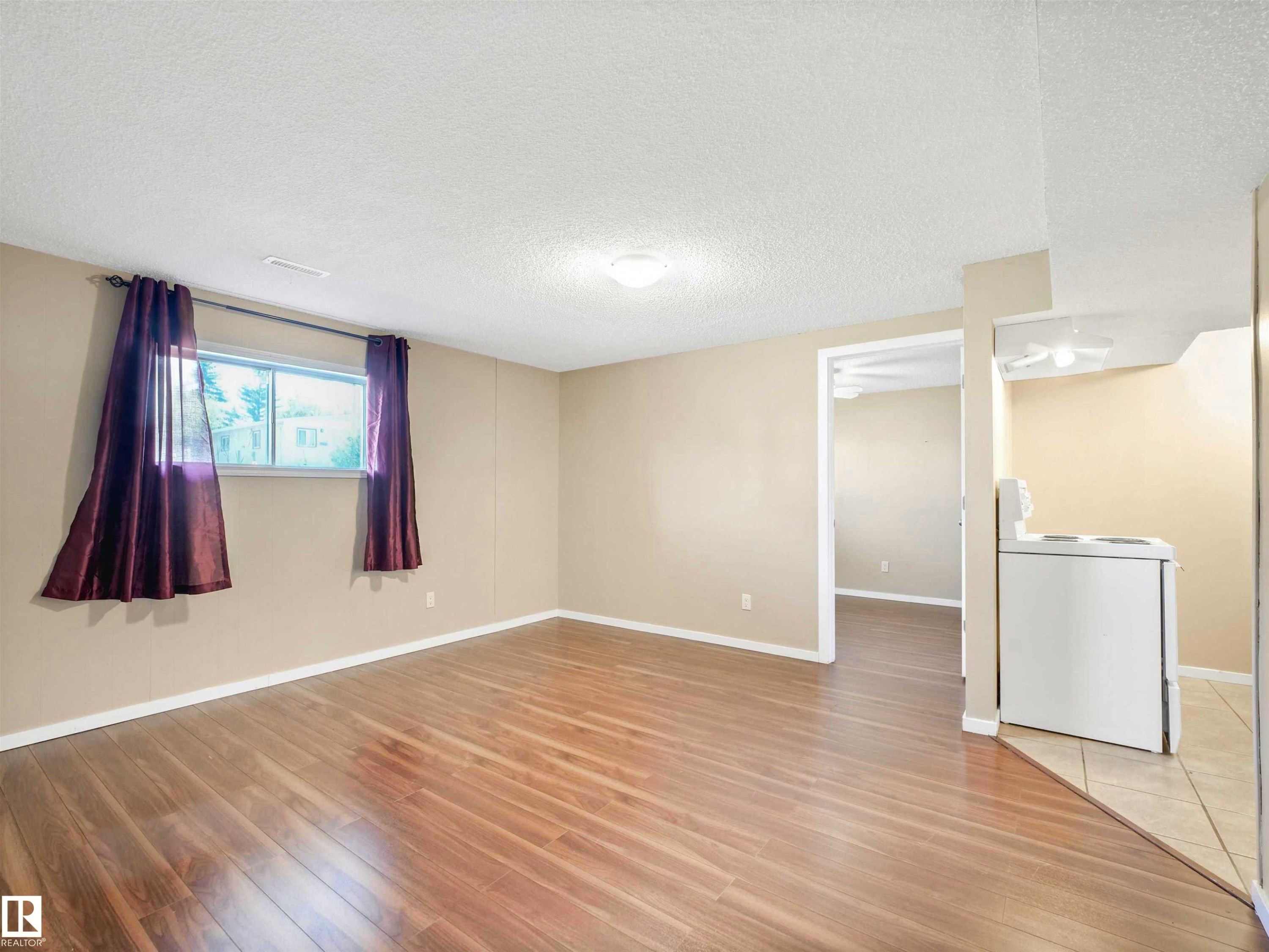 Hardwood-finish flooring extends through this room, complemented by a large window - 13114 30 Street, Edmonton, AB - Indoor Photo Showing Other Room