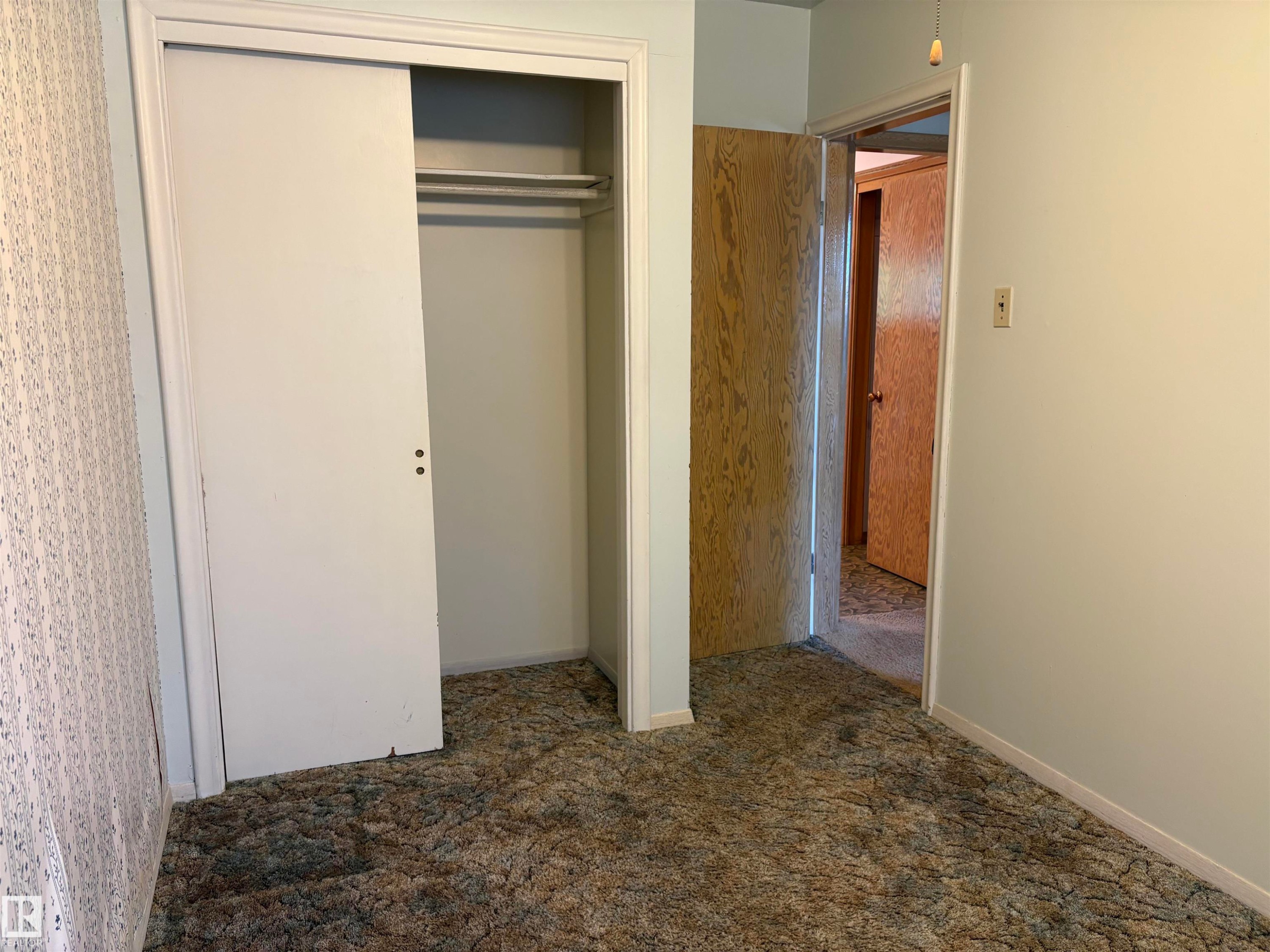 Bedroom featuring a double-door closet with sliding panels and interior hanging rods - 5511 50 St, Tofield, AB