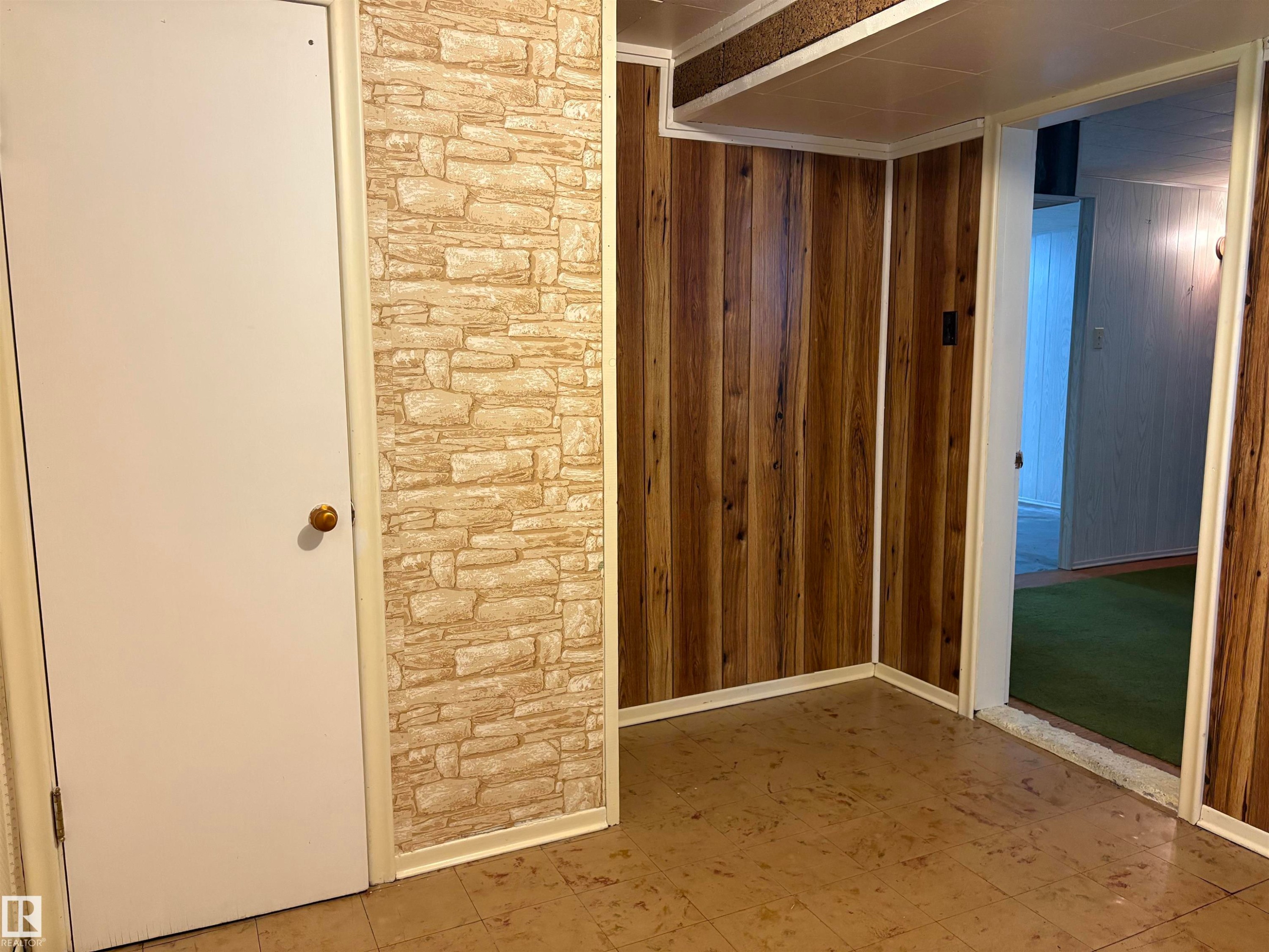 Interior space featuring wood-finish paneling, stone-look accent wall, and a solid white door - 5511 50 St, Tofield, AB