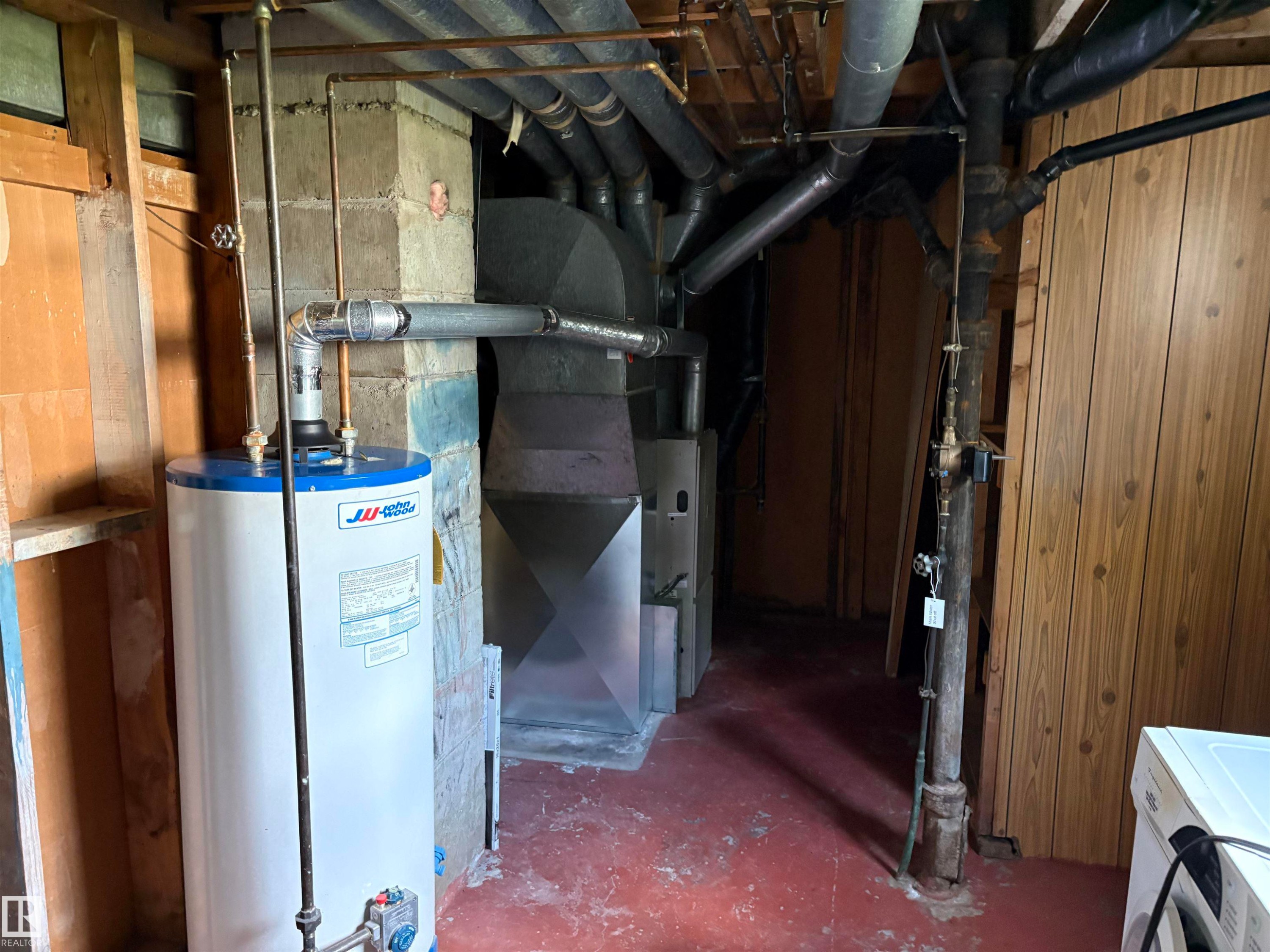 Utility area featuring a water heater, furnace, exposed ductwork, and concrete block walls - 5511 50 St, Tofield, AB