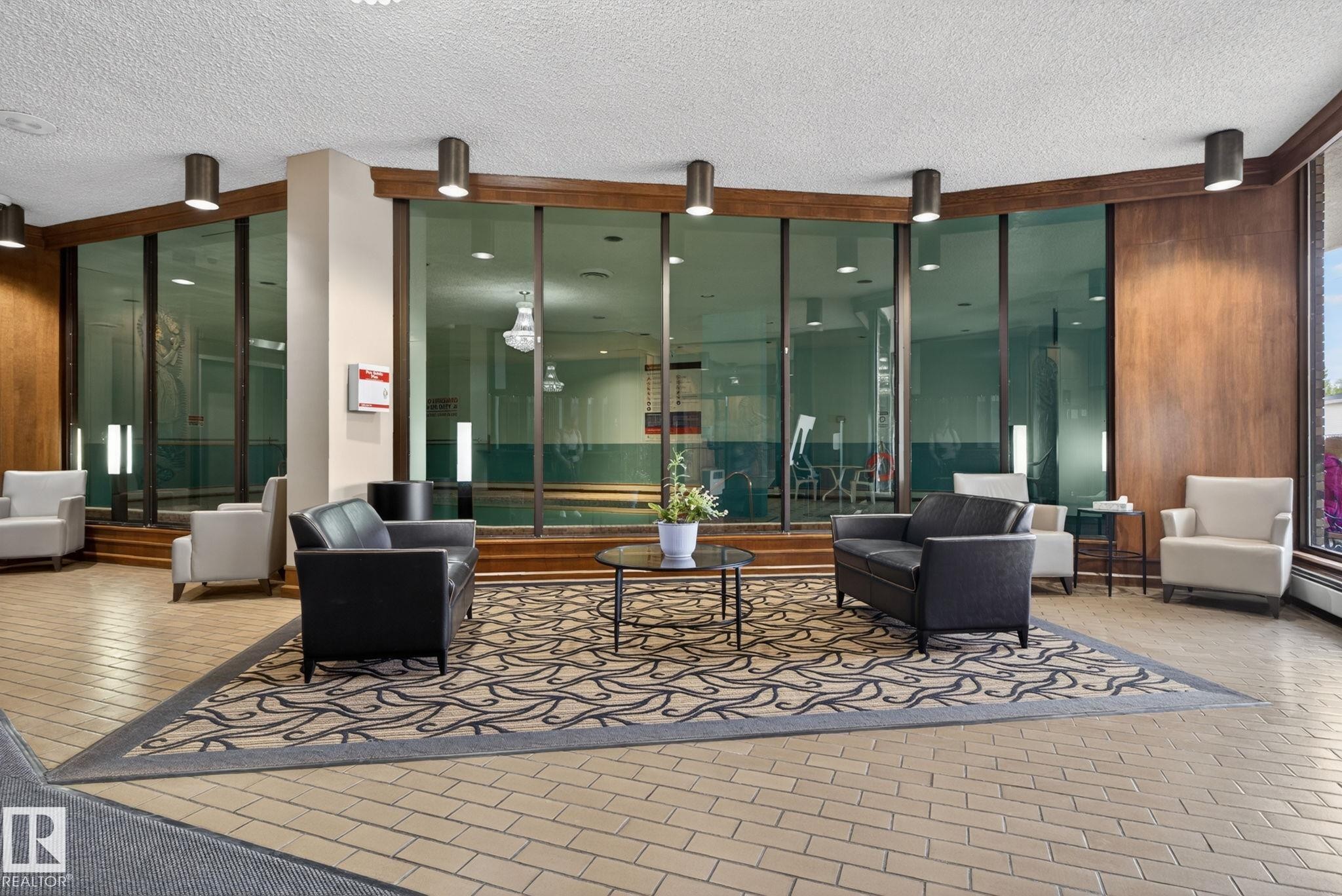 Lounge area featuring patterned carpeting, tile flooring, and wood-paneled walls - #412 13910 Stony Plain Rd Nw, Edmonton, AB - Indoor Photo Showing Other Room