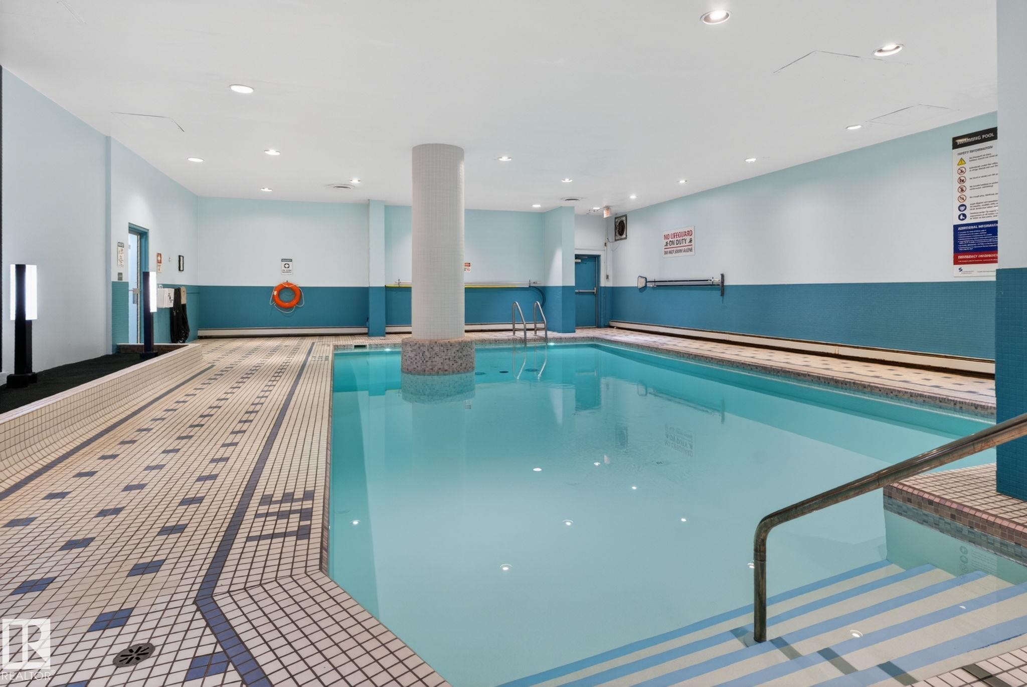 Indoor swimming pool featuring light blue walls and a patterned tile surround - #412 13910 Stony Plain Rd Nw, Edmonton, AB - Indoor Photo Showing Other Room With In Ground Pool