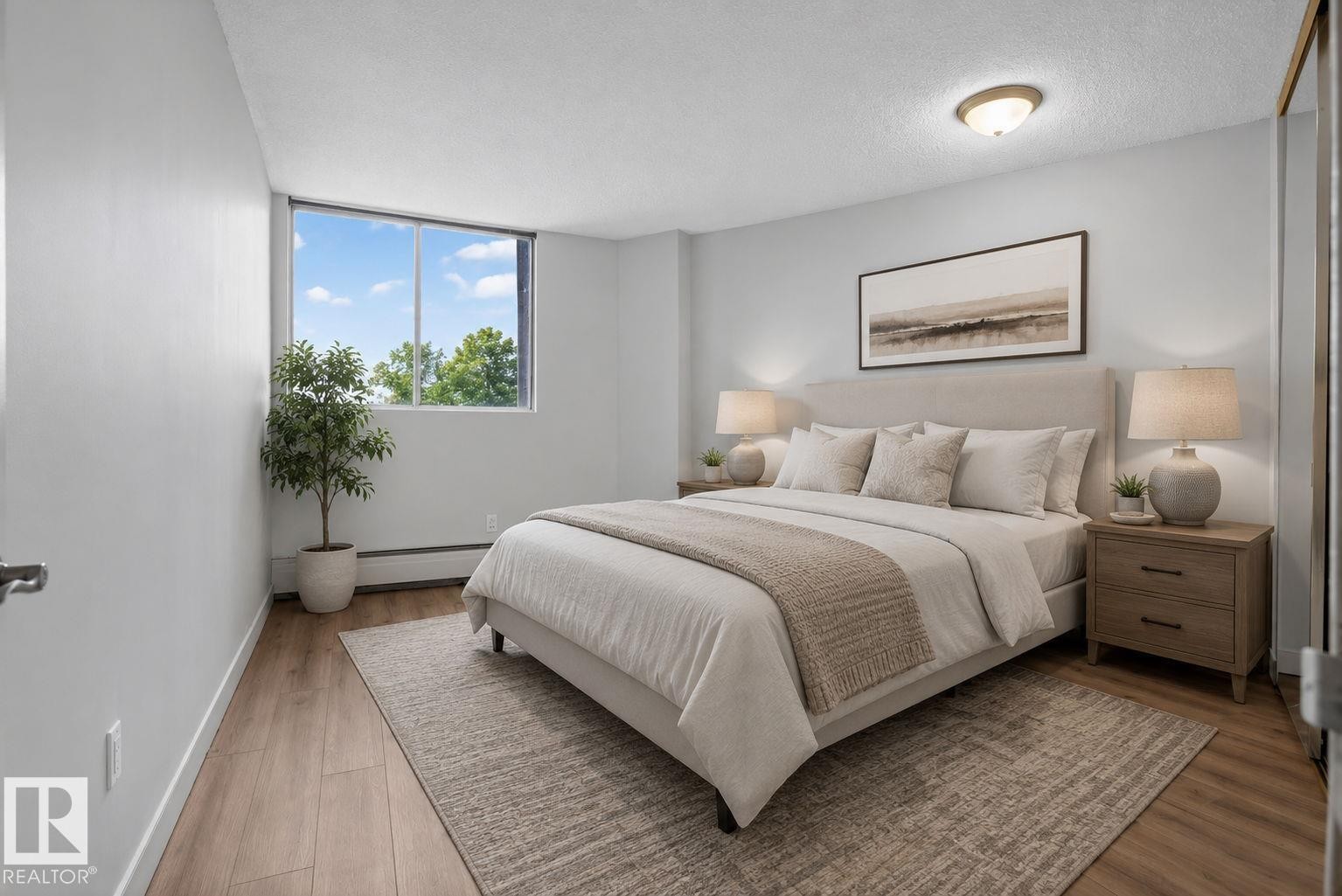 Spacious room featuring wood-finish flooring, a large window, light-colored walls, and a ceiling-mounted light fixture - #412 13910 Stony Plain Rd Nw, Edmonton, AB - Indoor Photo Showing Bedroom