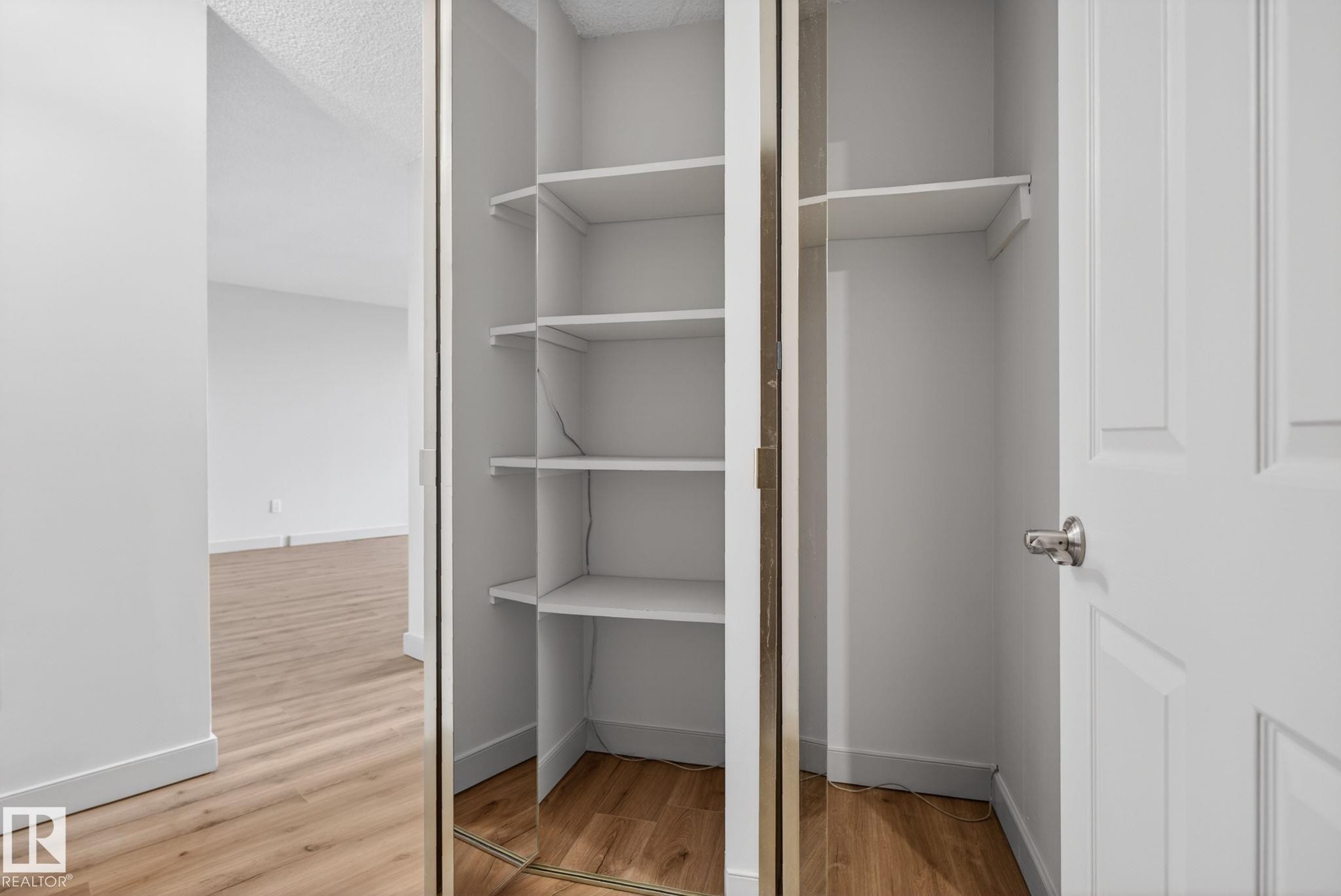 Built-in closet shelving with mirrored sliding doors - #412 13910 Stony Plain Rd Nw, Edmonton, AB - Indoor