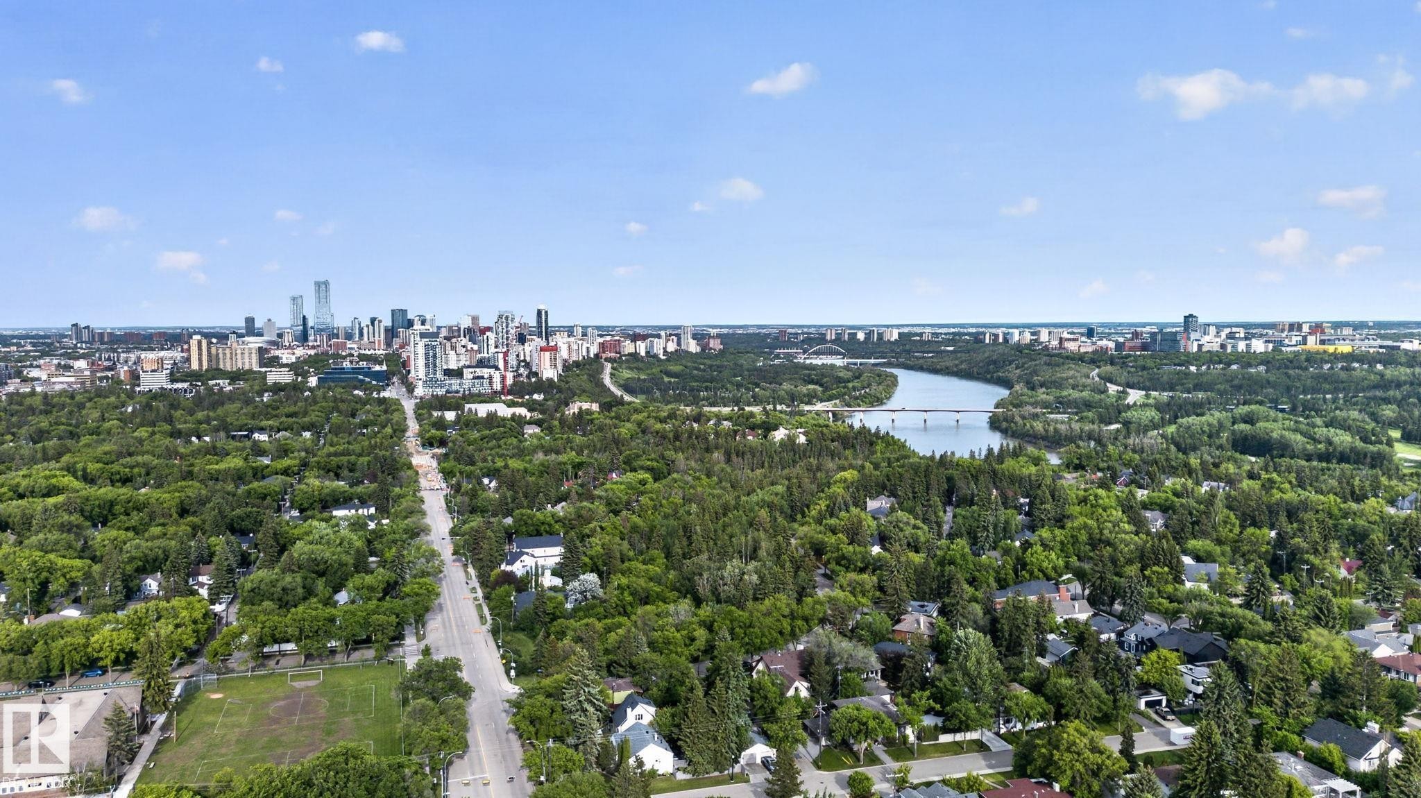 Expansive aerial perspective showcasing a cityscape, a winding river with a bridge, and a broad tree-lined road - #412 13910 Stony Plain Rd Nw, Edmonton, AB - Outdoor With View