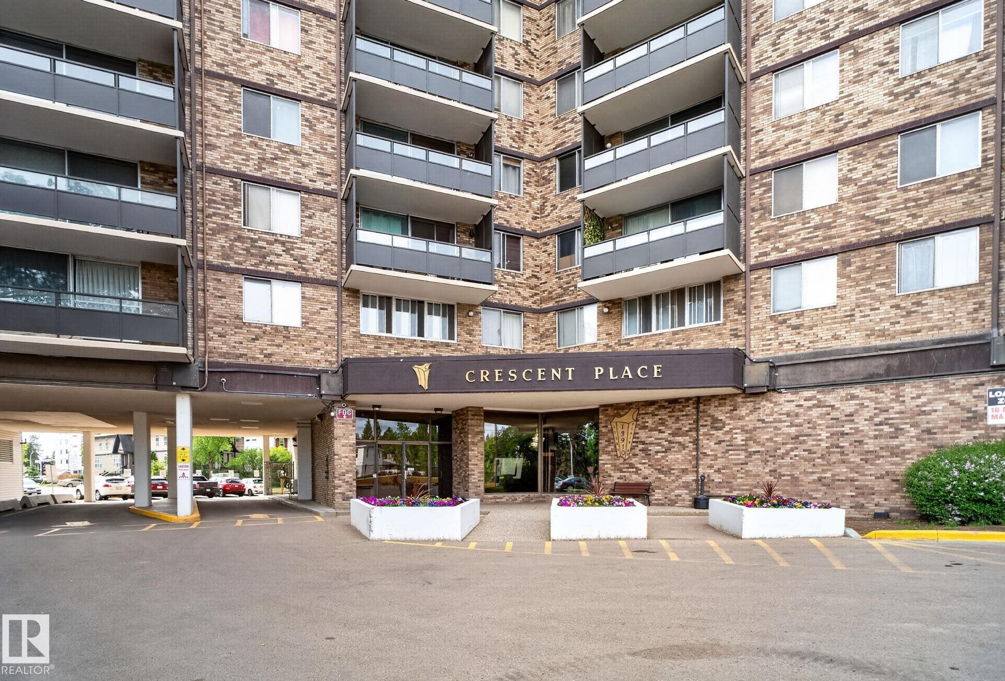 Brick facade building featuring a prominent main entrance with a "Crescent Place" sign - #412 13910 Stony Plain Rd Nw, Edmonton, AB - Outdoor With Balcony With Facade