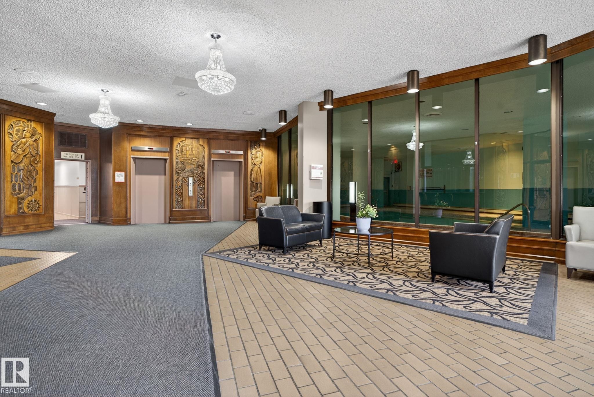 Lobby featuring wood-paneled walls with carved accents, two elevators, and a tiled floor - #412 13910 Stony Plain Rd Nw, Edmonton, AB - Indoor Photo Showing Other Room