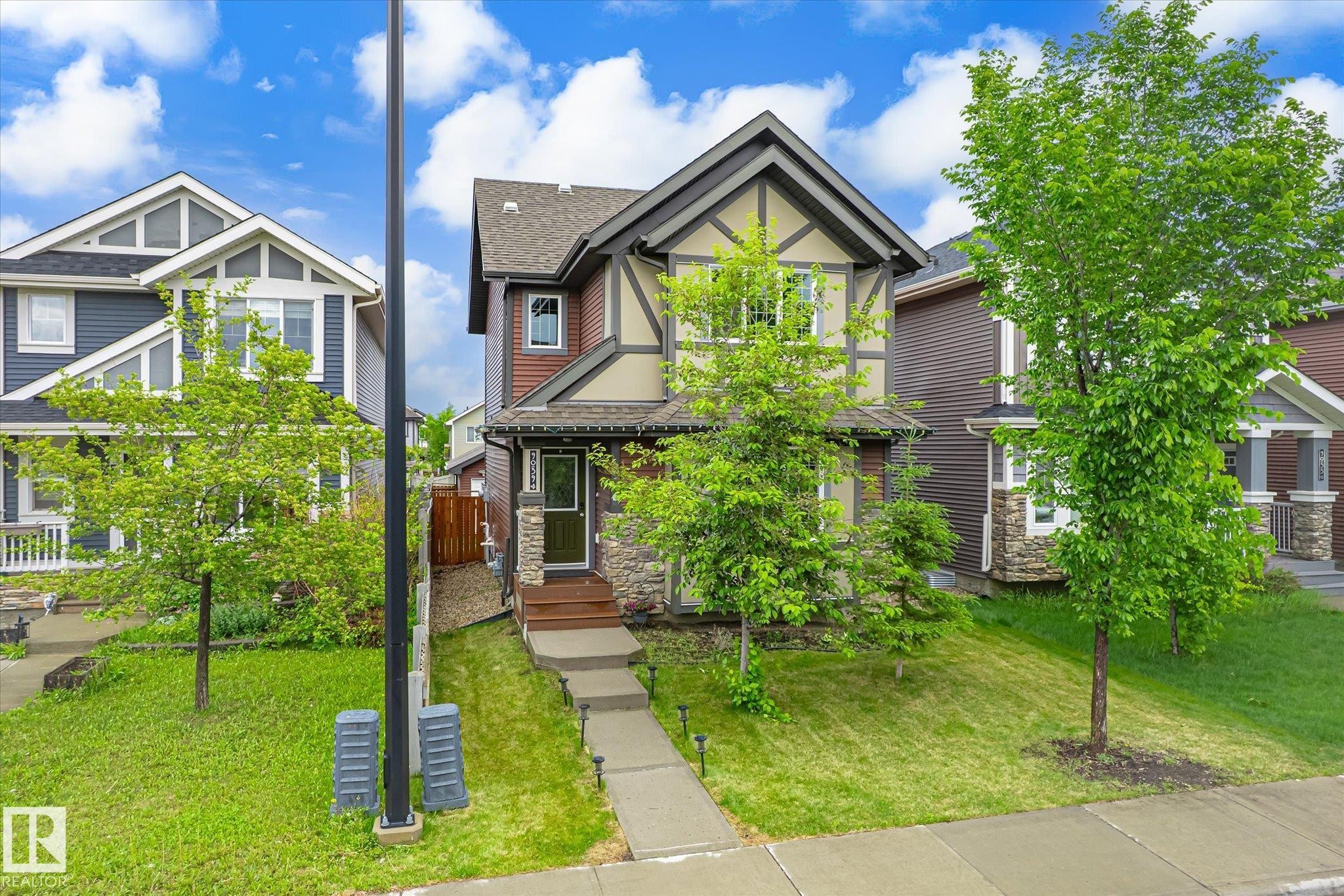 Craftsman-style exterior with stone and wood siding accents, featuring a gabled roofline - 9039 219 Street, Edmonton, AB