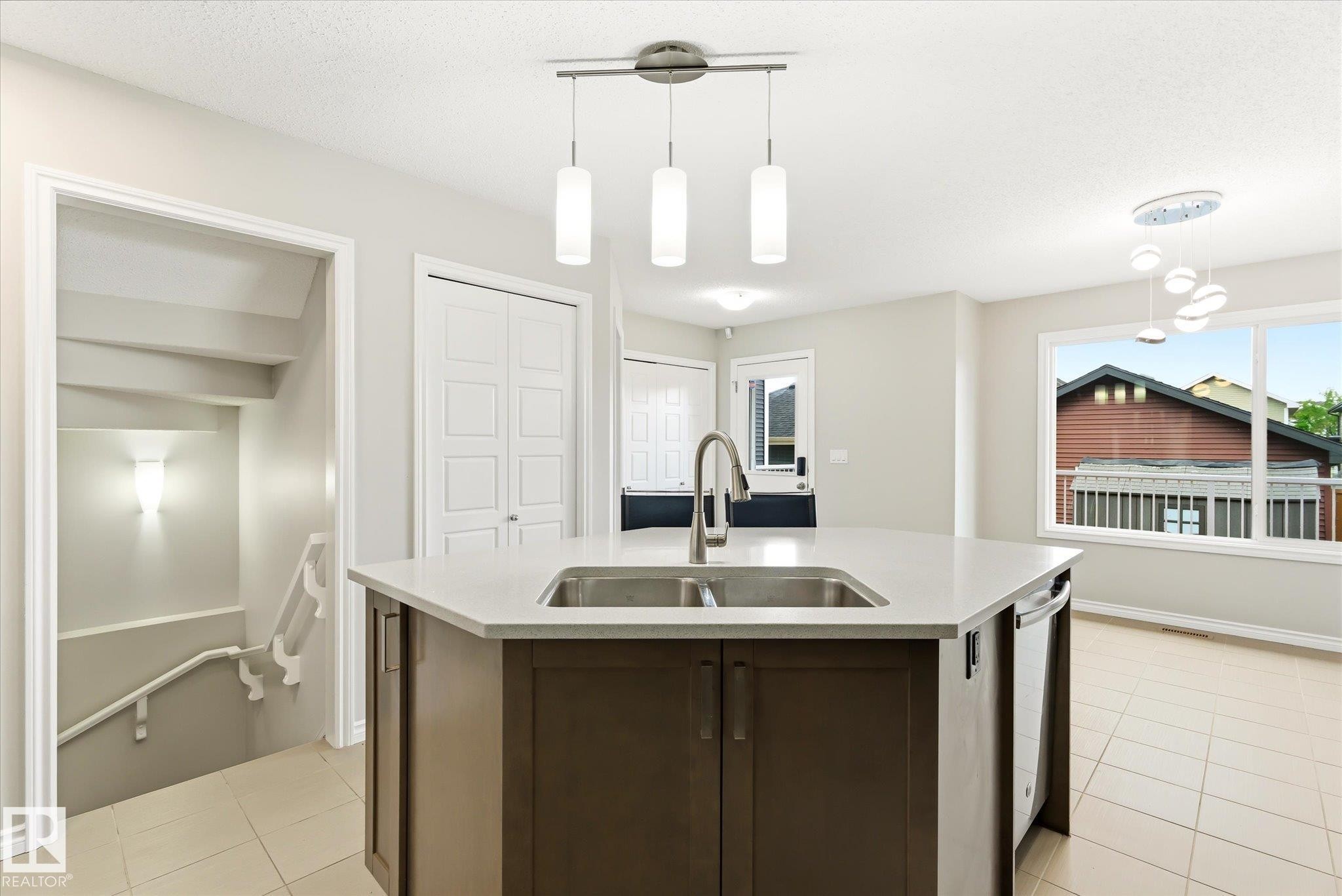 Kitchen island featuring a double-basin sink and integrated dishwasher - 9039 219 Street, Edmonton, AB
