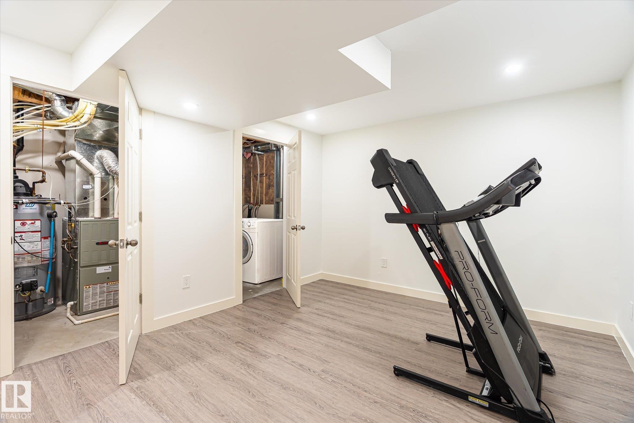 Finished basement space with wood-finish flooring, recessed lighting, and white baseboards - 9039 219 Street, Edmonton, AB