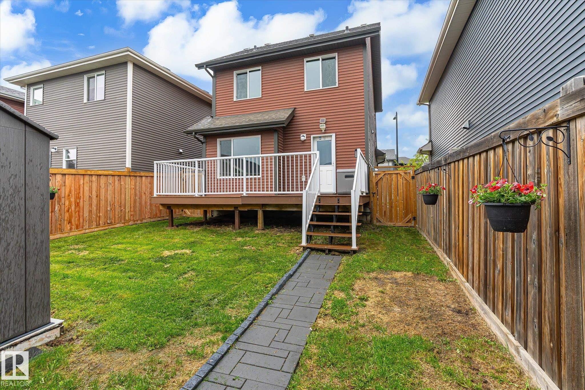 Expansive rear yard featuring a wood-finish fence, a paver stone pathway, and a detached storage shed - 9039 219 Street, Edmonton, AB