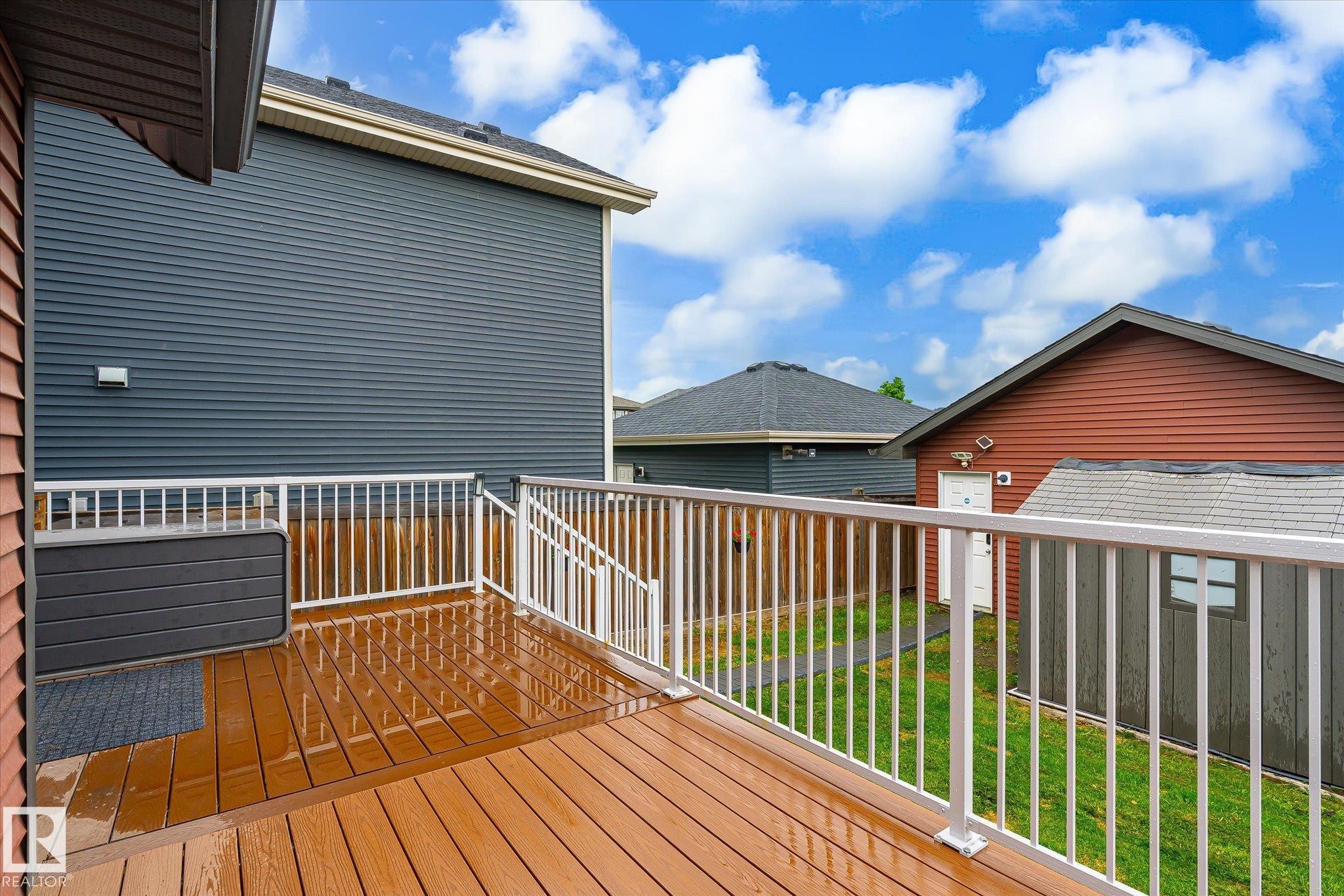 Outdoor deck featuring composite flooring, white railings, and a red siding exterior - 9039 219 Street, Edmonton, AB