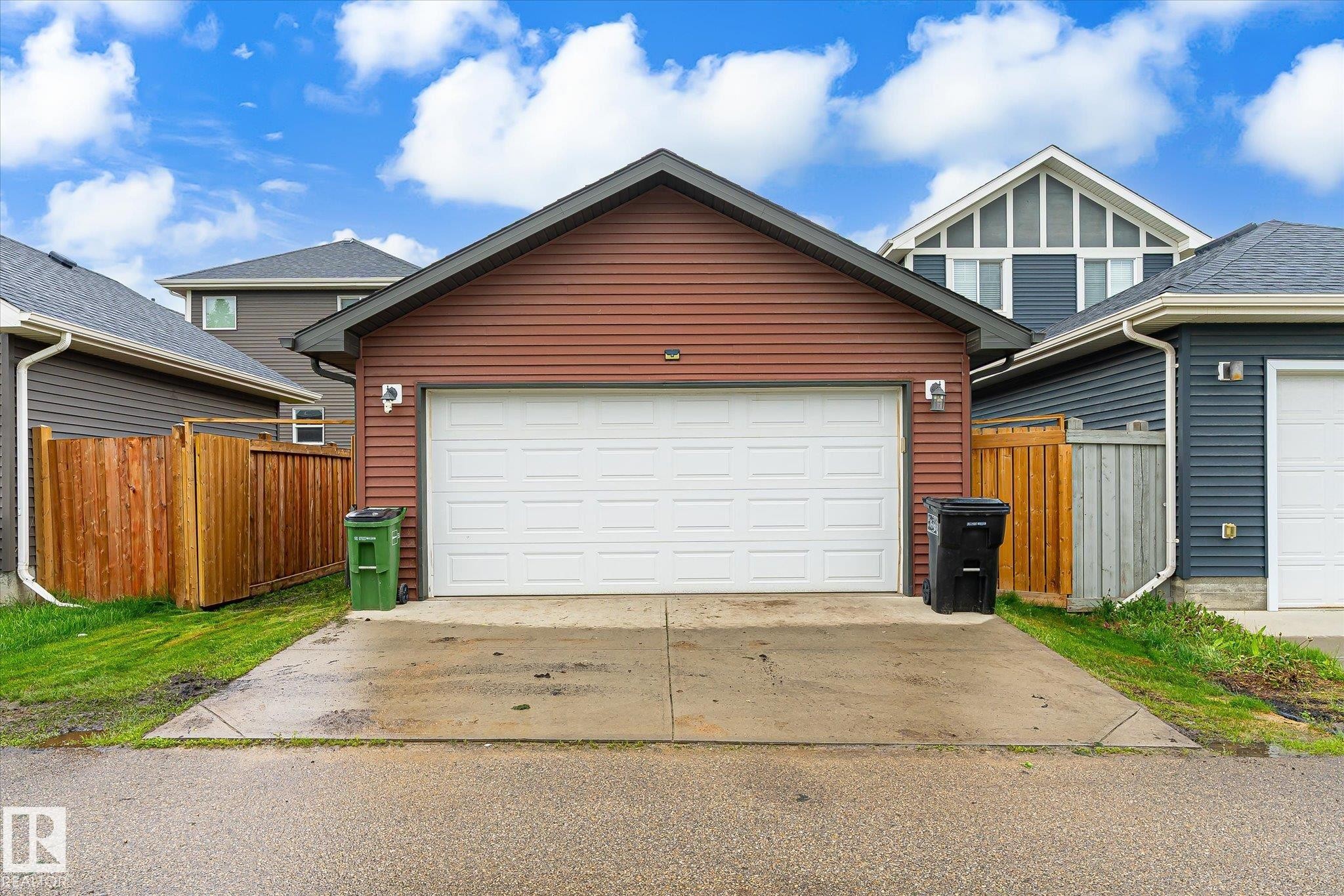 Detached garage with horizontal siding, a white sectional overhead door, and a concrete driveway - 9039 219 Street, Edmonton, AB