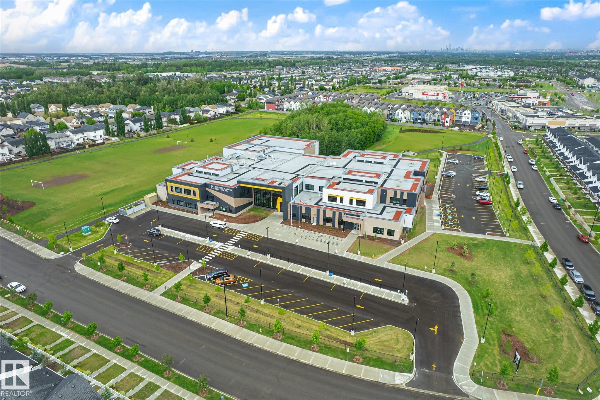 Contemporary commercial building featuring a multi-level roofline, extensive paved parking, and surrounding green spaces - 9039 219 Street, Edmonton, AB
