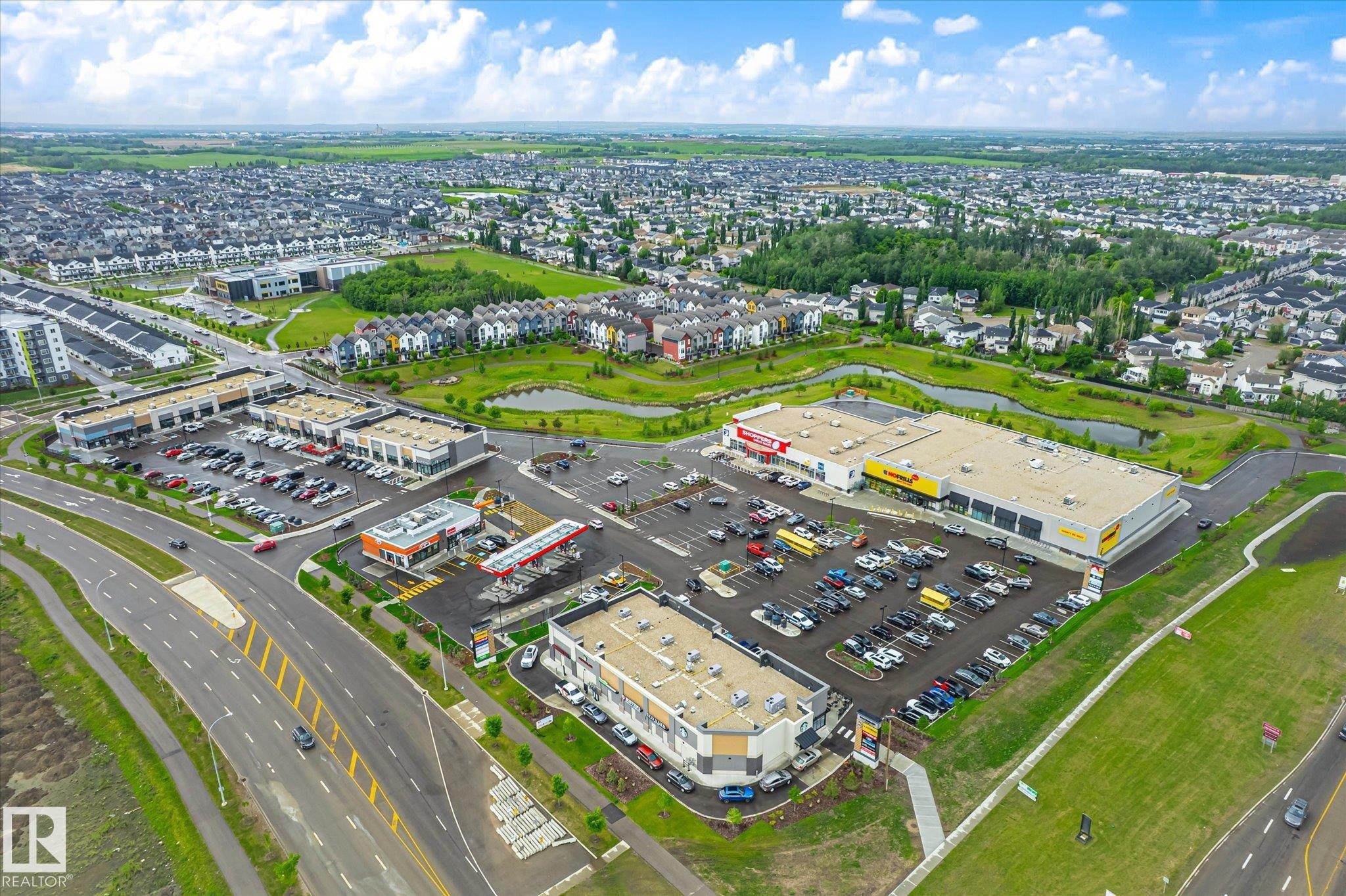 Aerial view of a commercial and residential area featuring multiple retail plazas, a gas station, a large grocery store, and extensive parking areas - 9039 219 Street, Edmonton, AB
