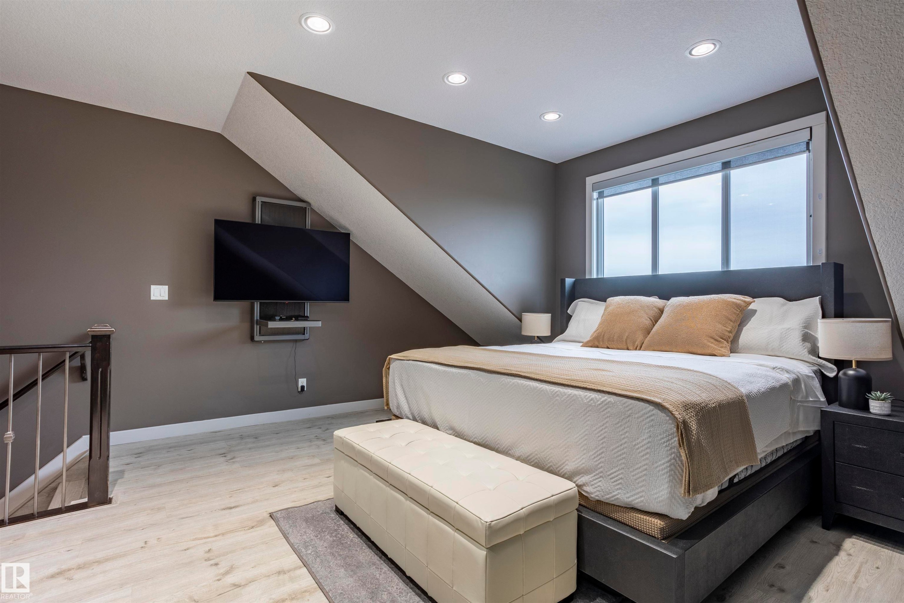 Spacious room featuring wood-finish flooring, recessed ceiling lights, a large window, and a built-in wall-mounted television unit - 4949 Terwillegar Common Nw, Edmonton, AB