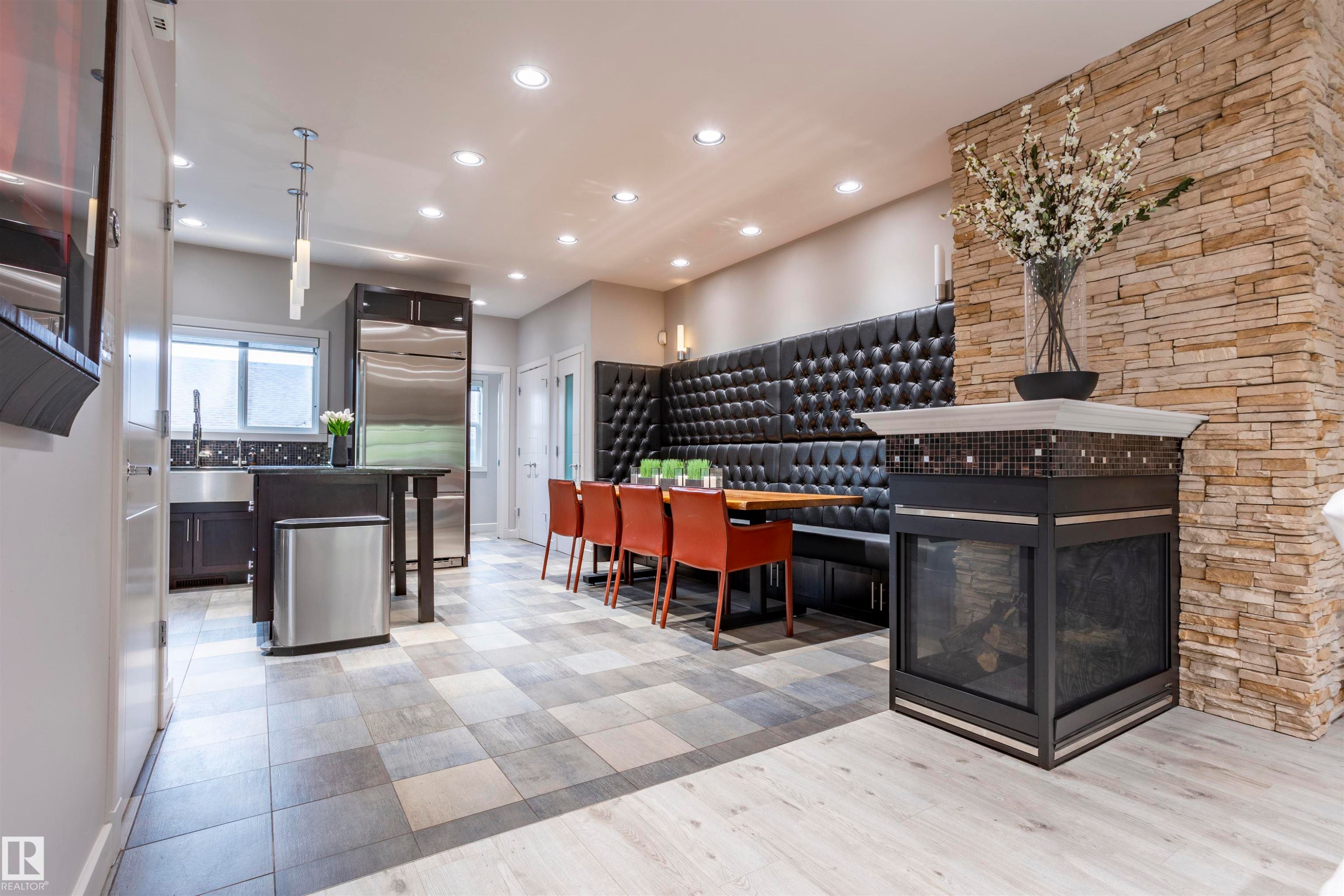 Kitchen and dining area featuring a stacked stone accent wall, built-in fireplace, and integrated booth seating - 4949 Terwillegar Common Nw, Edmonton, AB