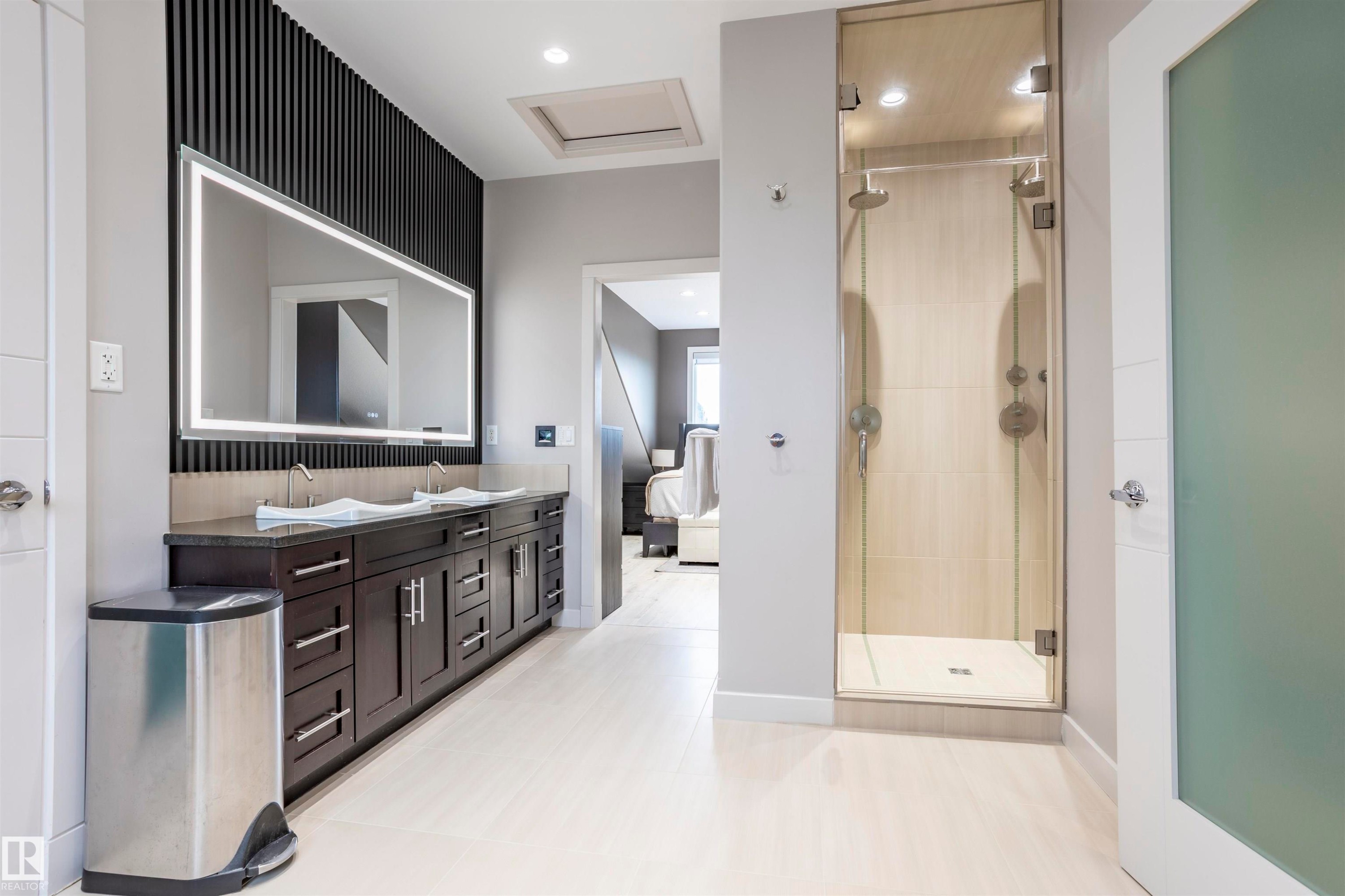 Contemporary bathroom featuring a dual vanity with dark wood cabinetry and a light-up mirror - 4949 Terwillegar Common Nw, Edmonton, AB