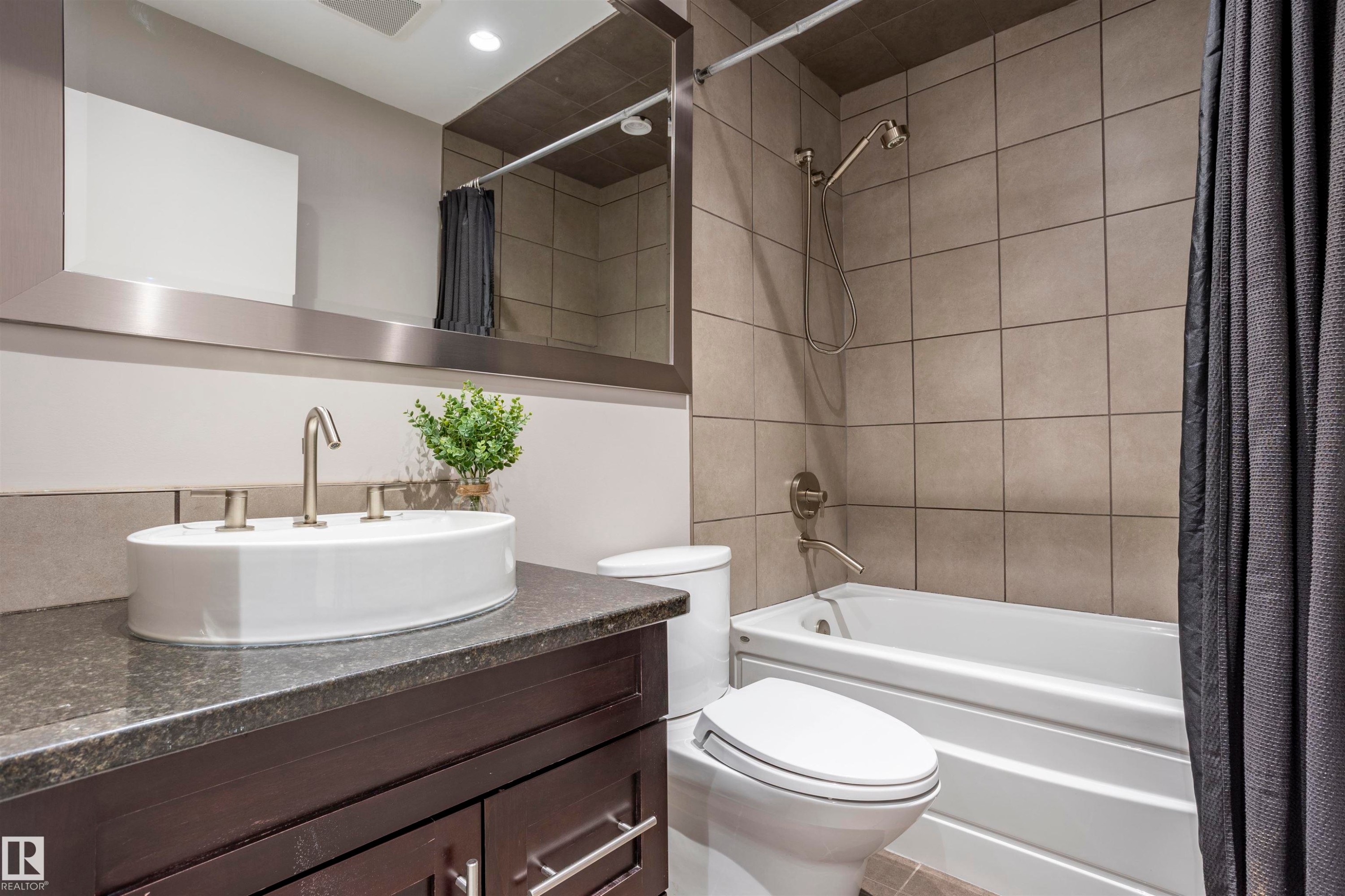 Bathroom featuring a white oval vessel sink, dark wood-finish vanity with chrome hardware, and a dark stone-finish countertop - 4949 Terwillegar Common Nw, Edmonton, AB