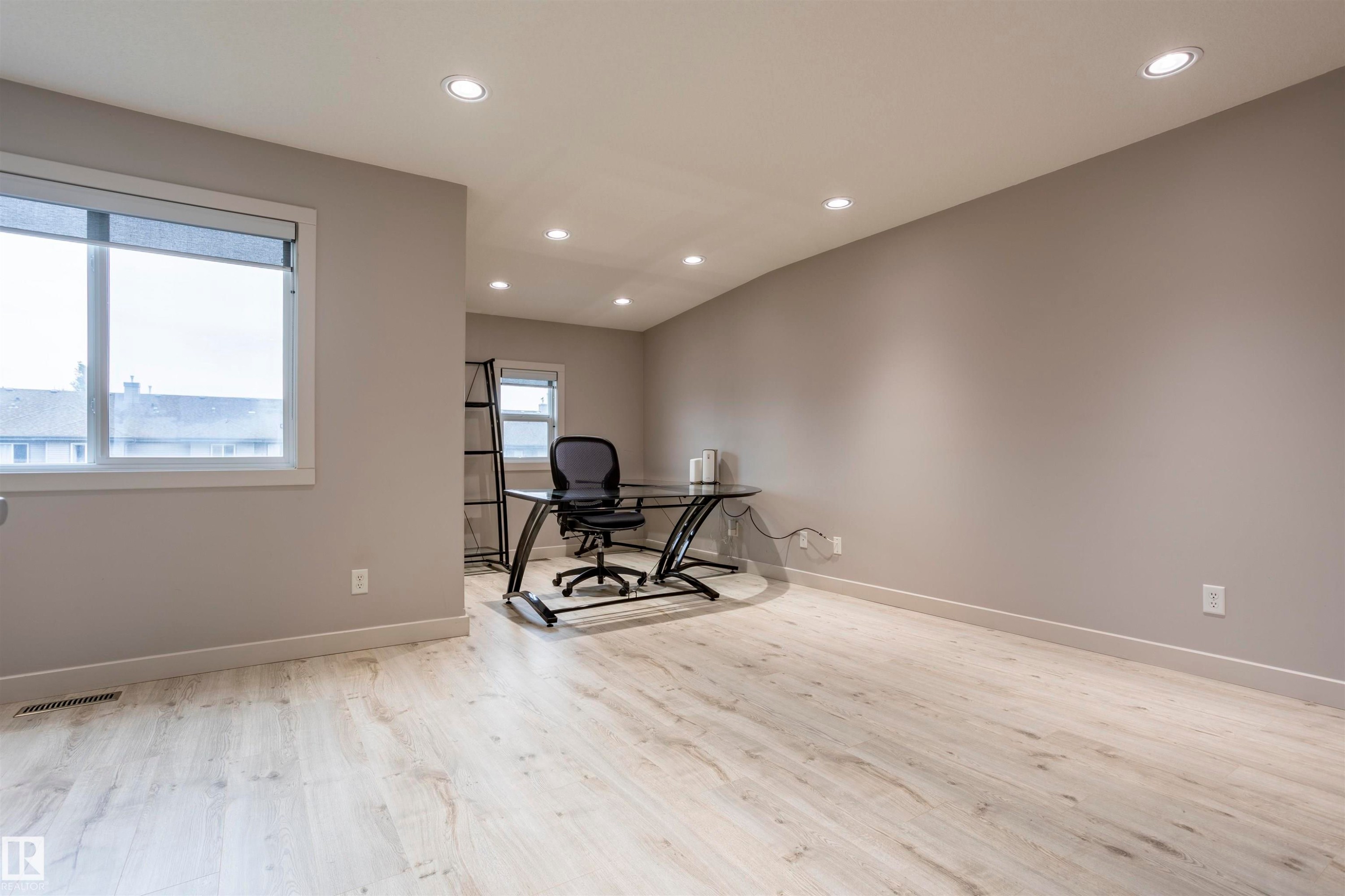 Spacious interior room featuring light wood-finish flooring, neutral wall paint, and recessed ceiling lighting - 4949 Terwillegar Common Nw, Edmonton, AB