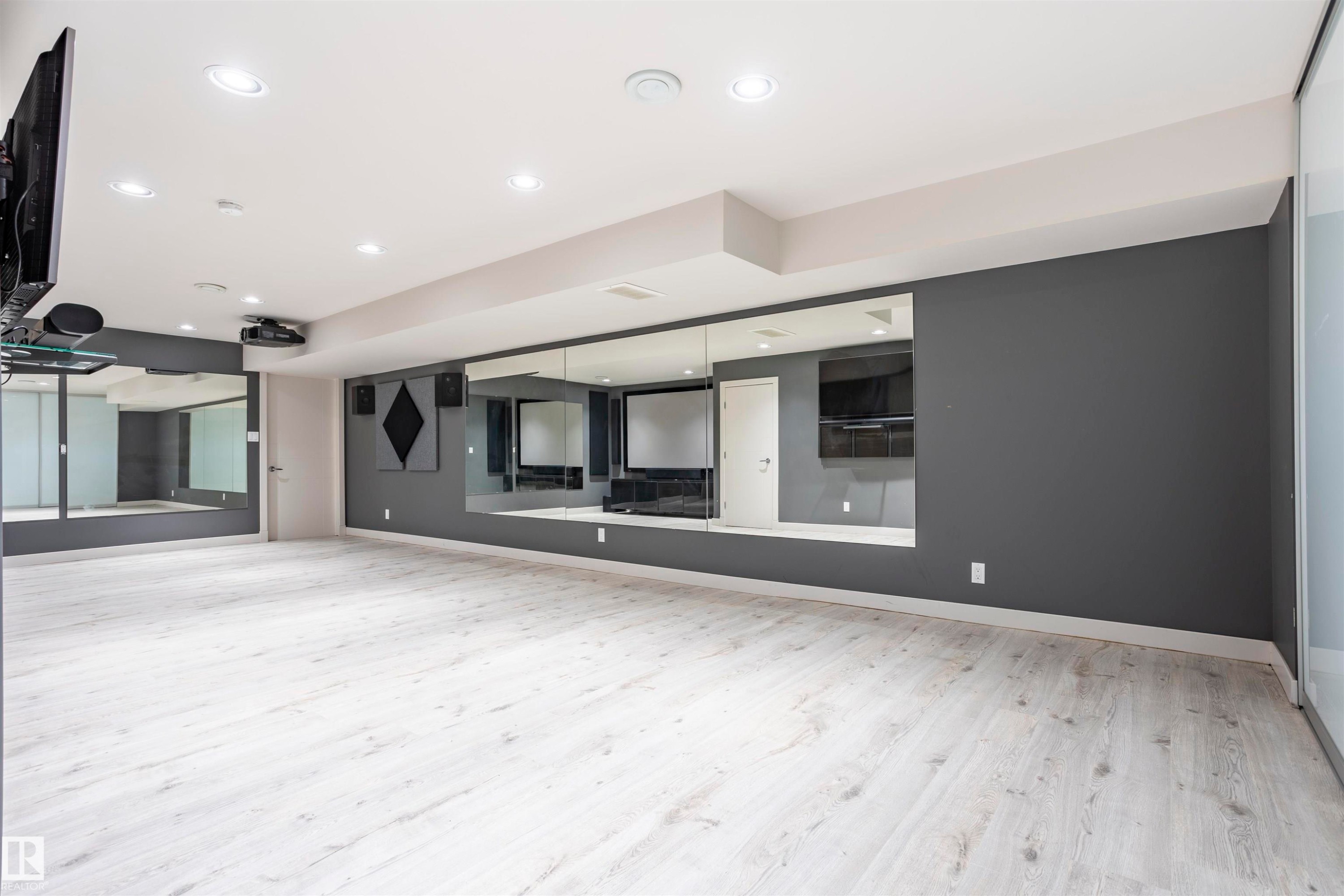 Open concept room featuring light wood-finish flooring, recessed lighting, and a mirrored wall - 4949 Terwillegar Common Nw, Edmonton, AB