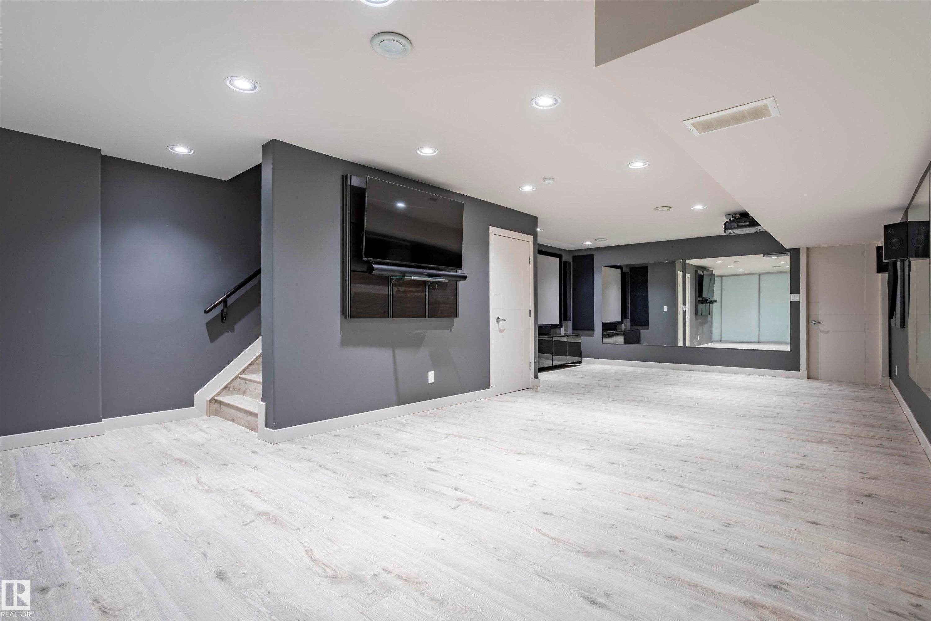 Spacious room featuring light wood-finish flooring, recessed lighting, and a wall-mounted media console - 4949 Terwillegar Common Nw, Edmonton, AB