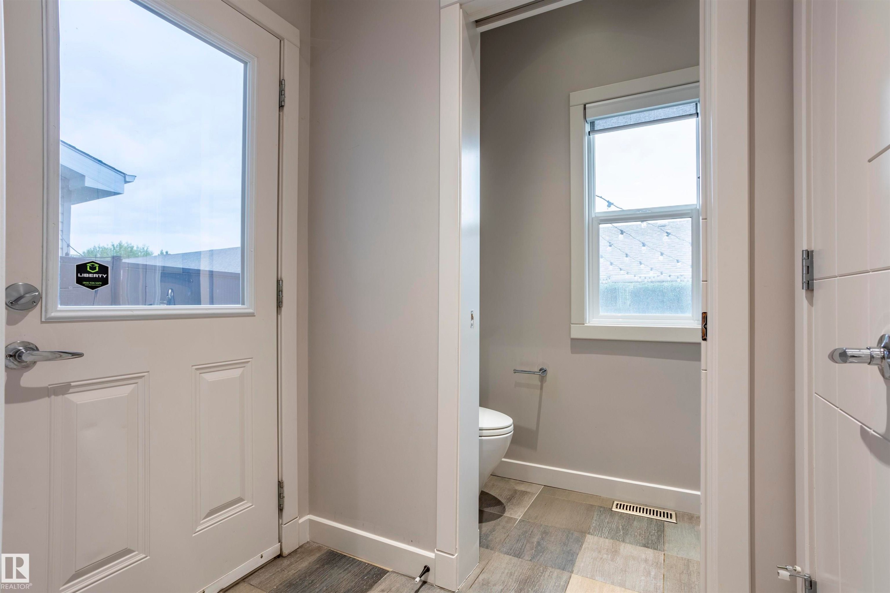 Entryway featuring a partially glazed door with silver-tone hardware, wood-finish flooring, and light neutral wall paint - 4949 Terwillegar Common Nw, Edmonton, AB