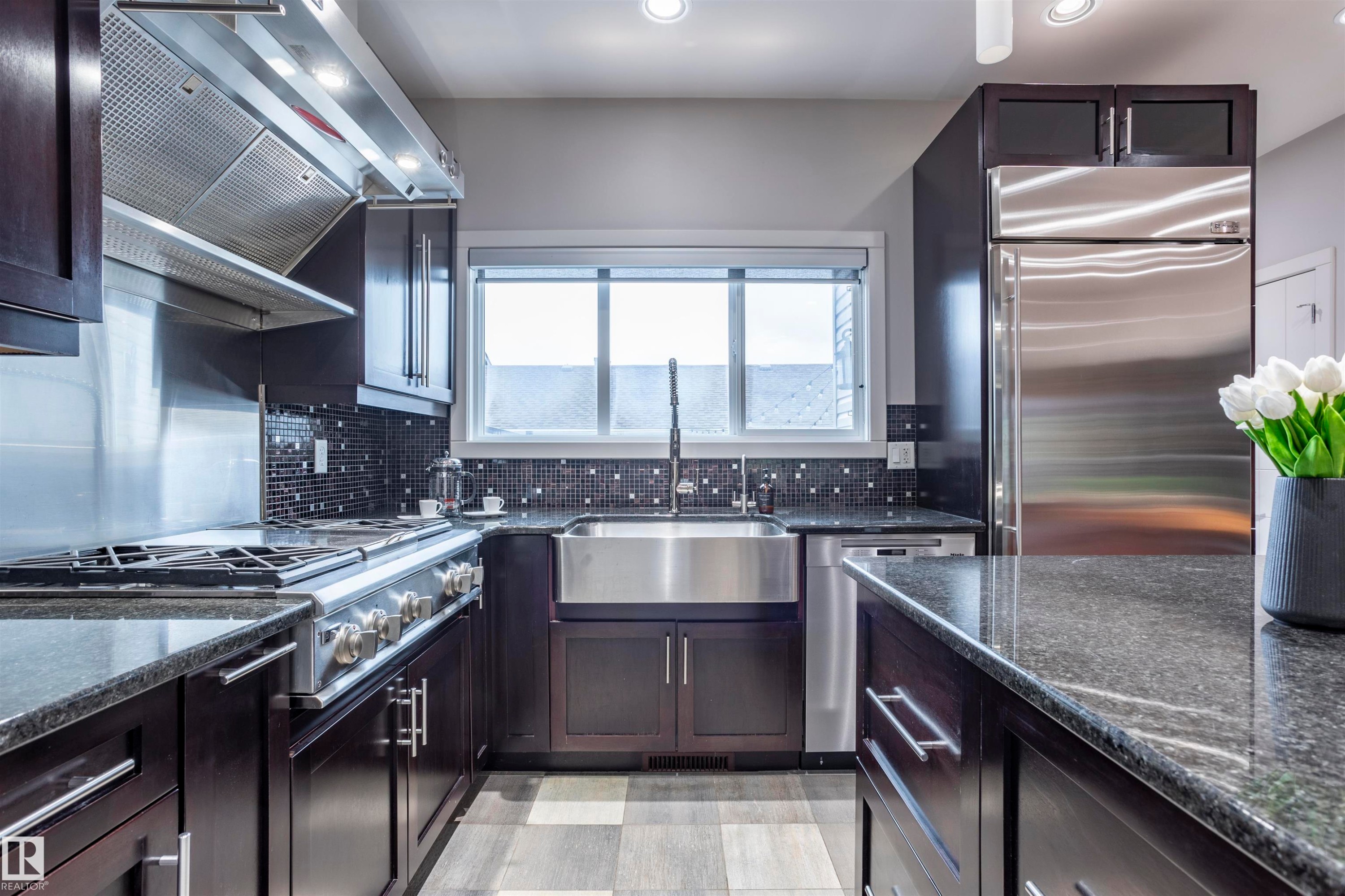 Modern kitchen featuring dark wood cabinetry, stainless steel appliances, and granite countertops - 4949 Terwillegar Common Nw, Edmonton, AB
