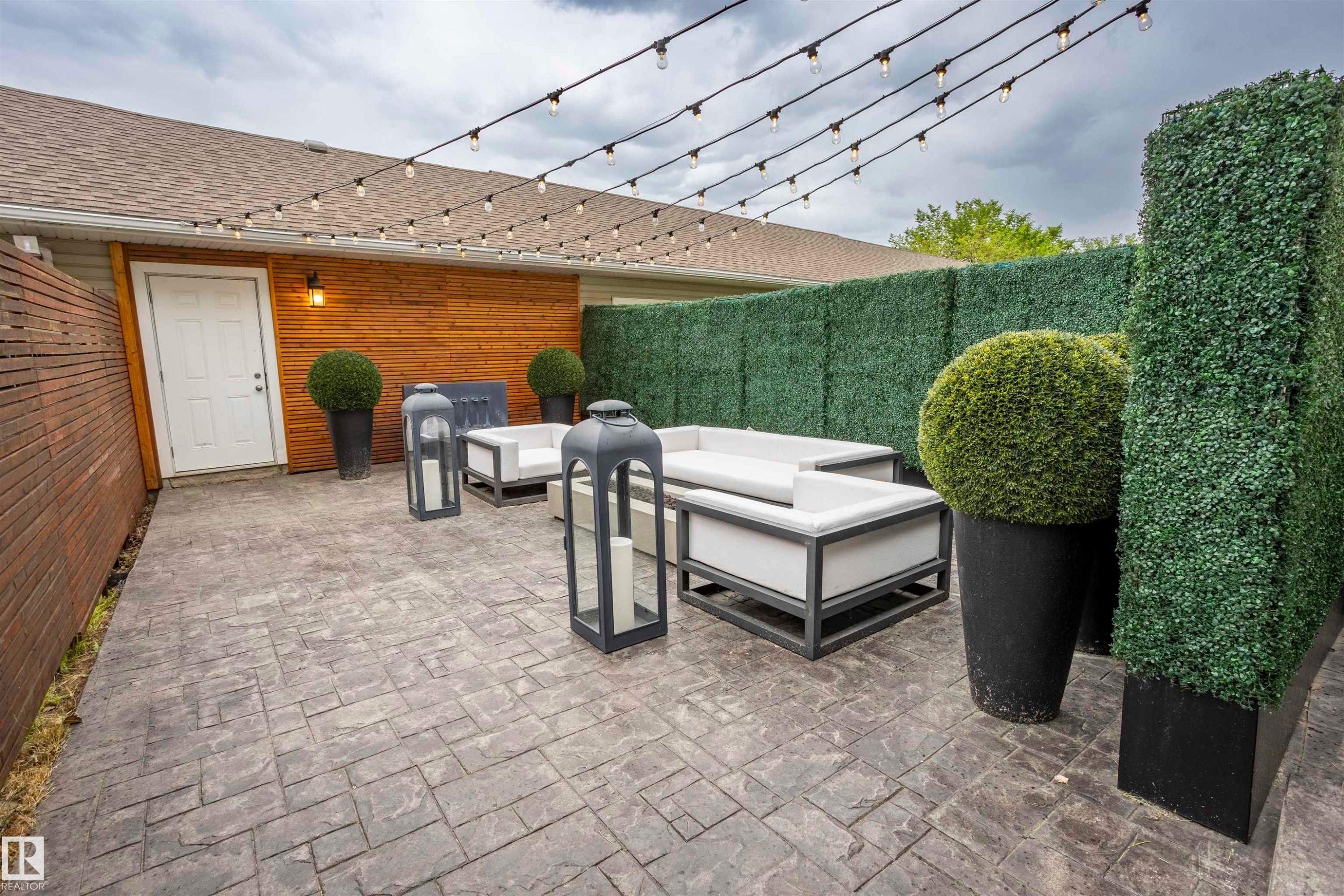 Expansive stamped concrete patio featuring a wood-panel accent wall and a privacy fence - 4949 Terwillegar Common Nw, Edmonton, AB