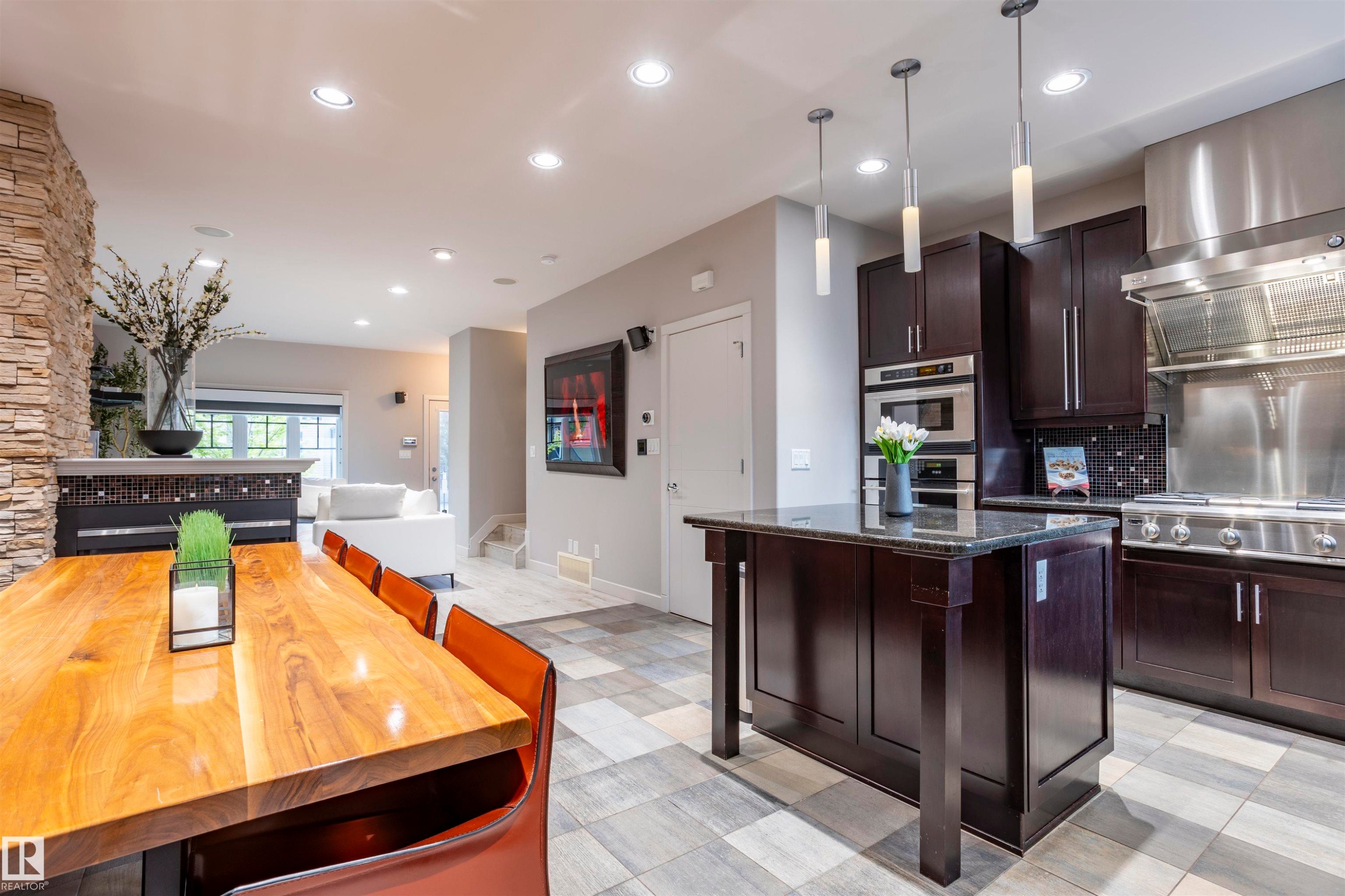Gourmet kitchen with dark wood cabinetry, stainless steel appliances, and a central island with a dark countertop - 4949 Terwillegar Common Nw, Edmonton, AB