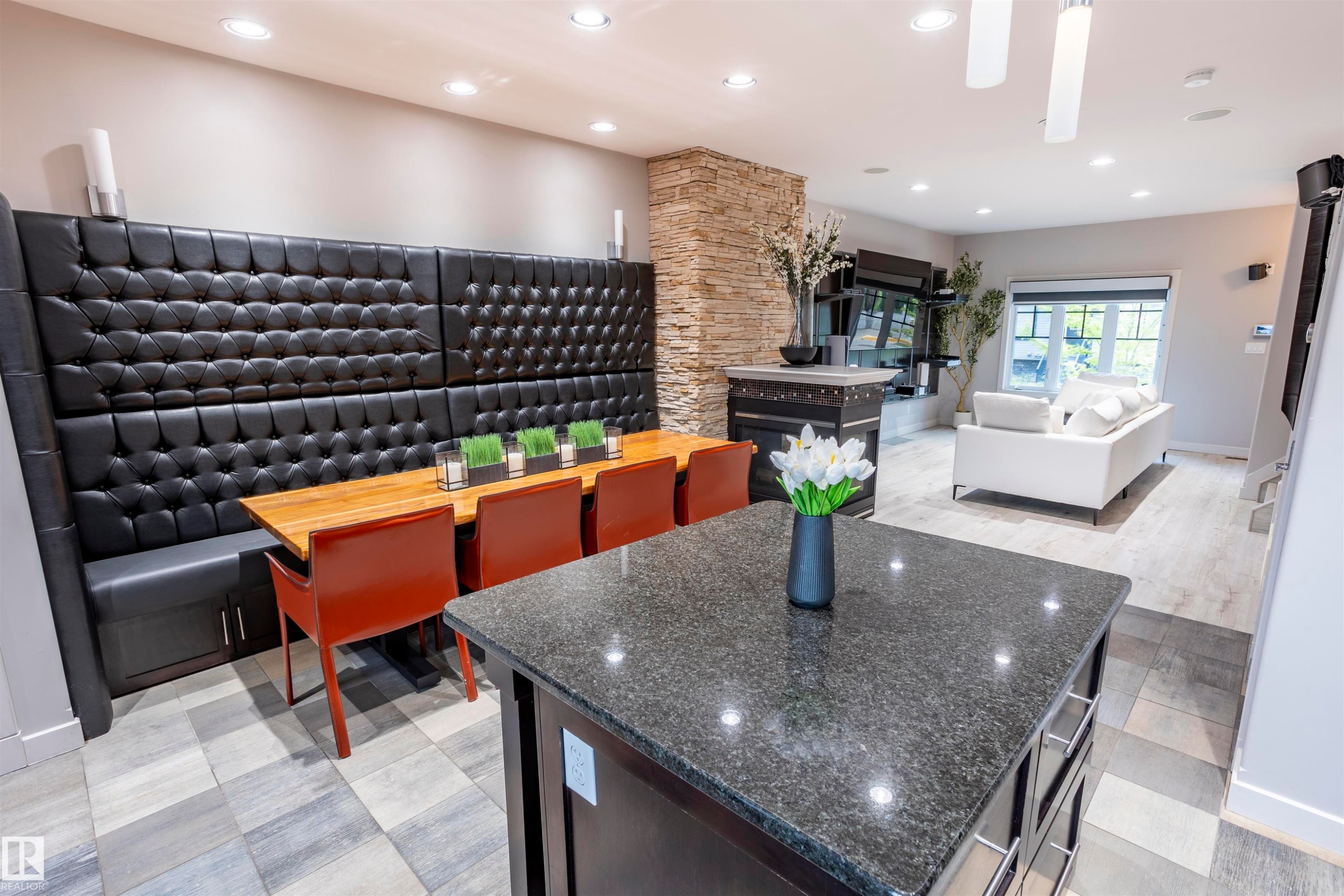 Kitchen island with a dark granite countertop and integrated cabinetry, paired with a custom built-in dining banquette featuring black tufted upholstery - 4949 Terwillegar Common Nw, Edmonton, AB