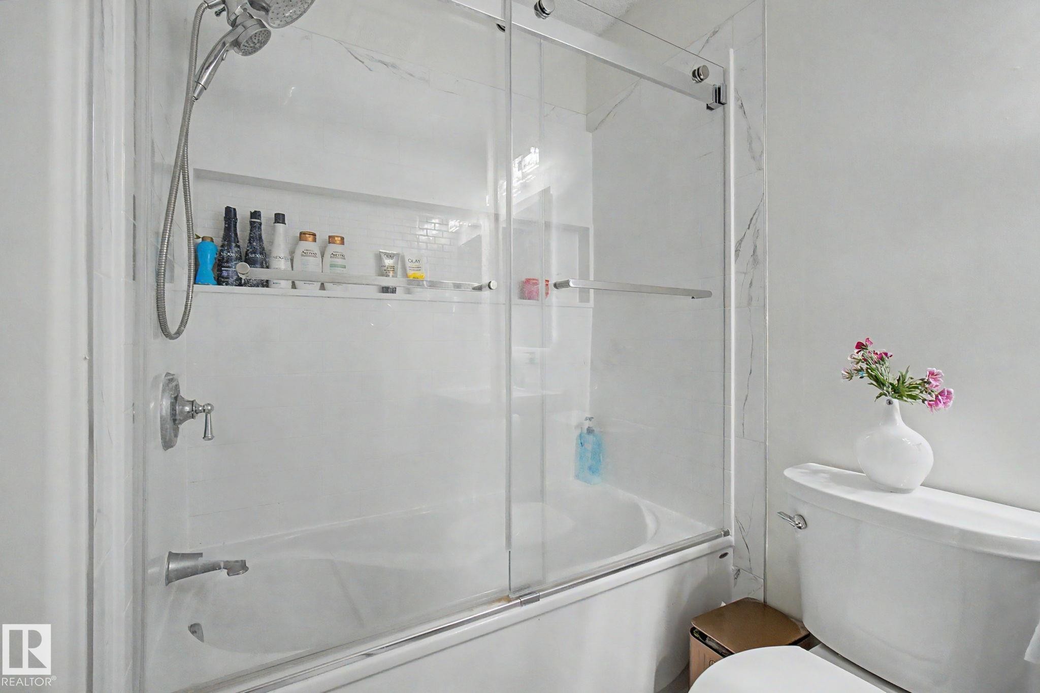 Bathtub with sliding glass enclosure and integrated shower niche - 710 Glenwright Court, Edmonton, AB