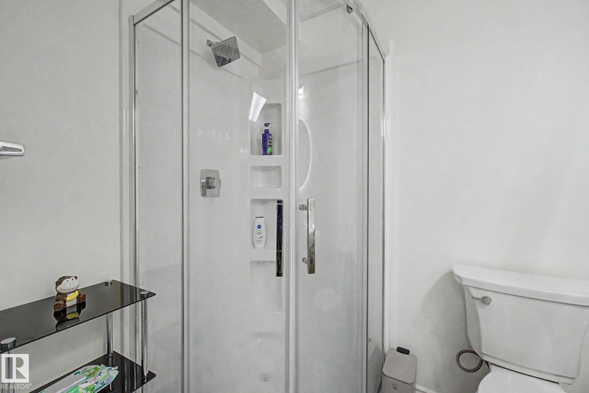 Corner shower enclosure featuring clear glass panels and a chrome-finish shower head - 710 Glenwright Court, Edmonton, AB