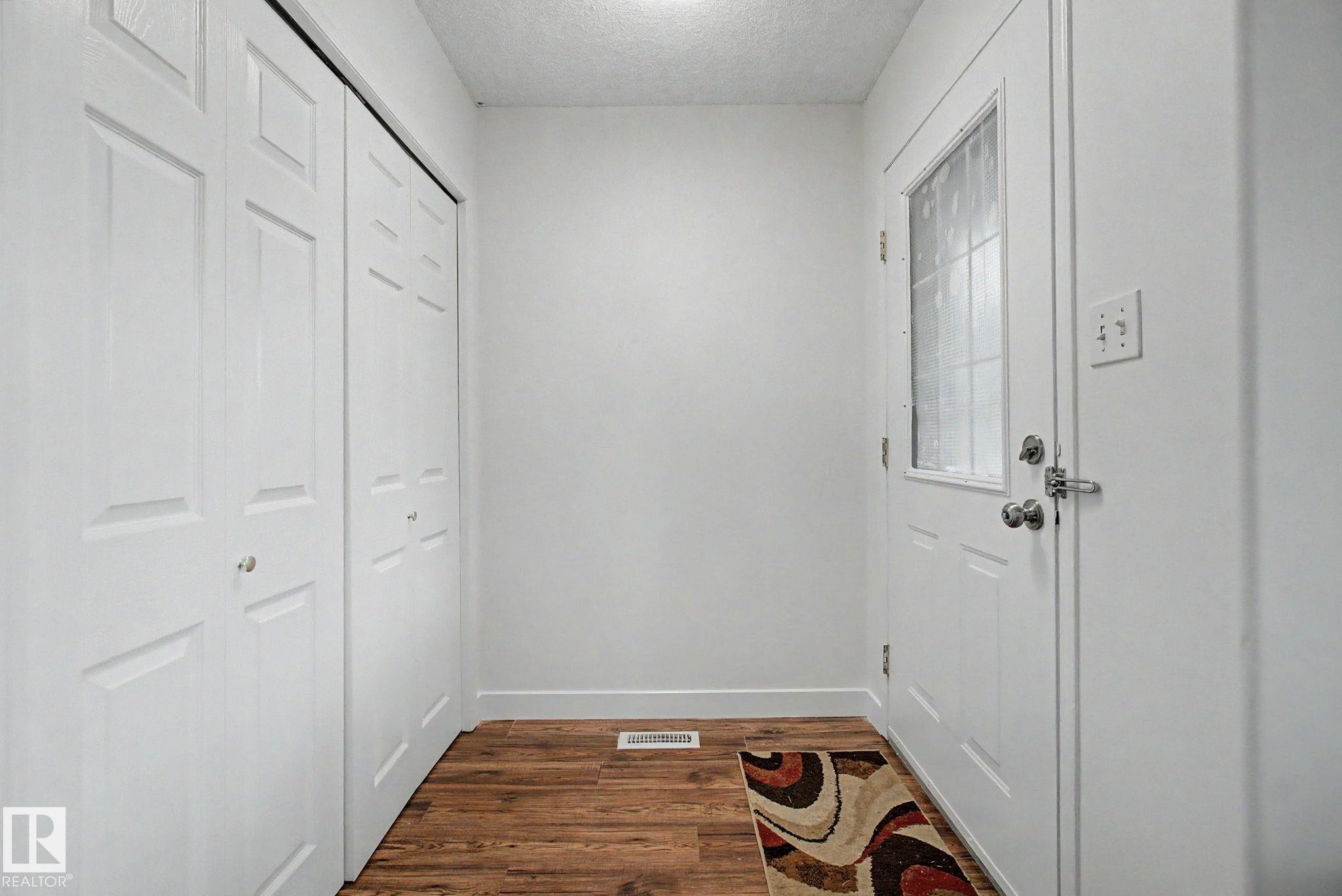 Entryway with wood-finish flooring, a white paneled door with frosted glass insert, and bi-fold closet doors - 710 Glenwright Court, Edmonton, AB