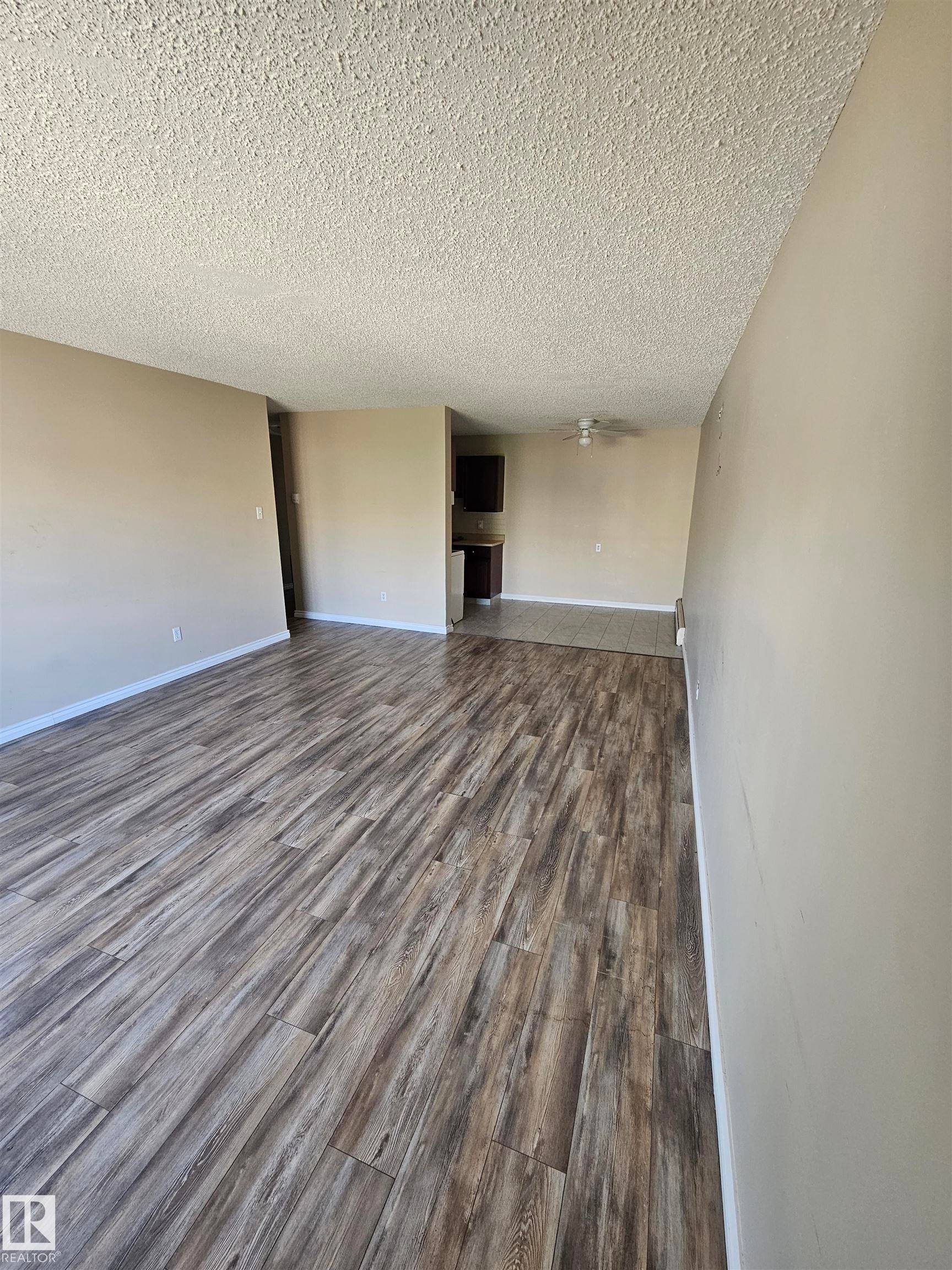 Spacious interior featuring wood-finish flooring, neutral wall paint, and a textured ceiling - #301 10615 110 Street Nw Nw, Edmonton, AB - Indoor Photo Showing Other Room