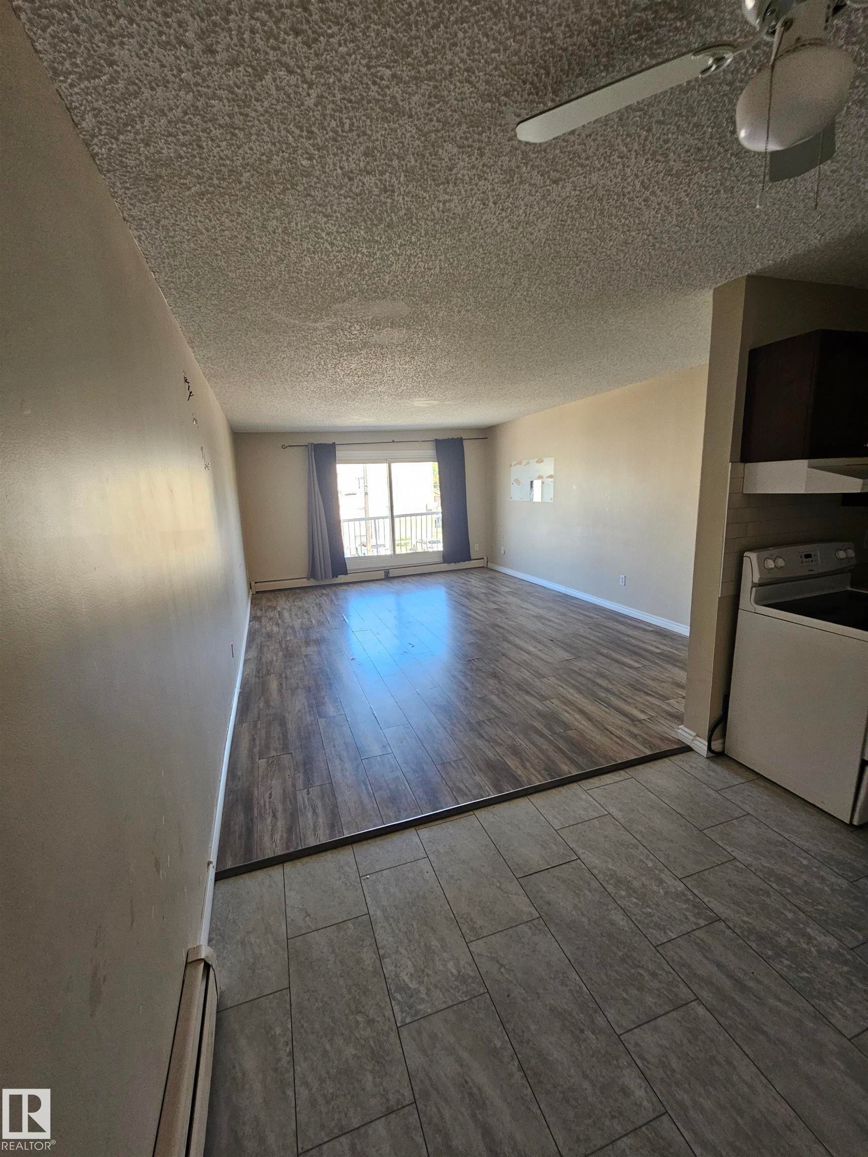Open-concept living area featuring wood-finish flooring, a ceiling fan, and a balcony with a metal railing - #301 10615 110 Street Nw Nw, Edmonton, AB - Indoor