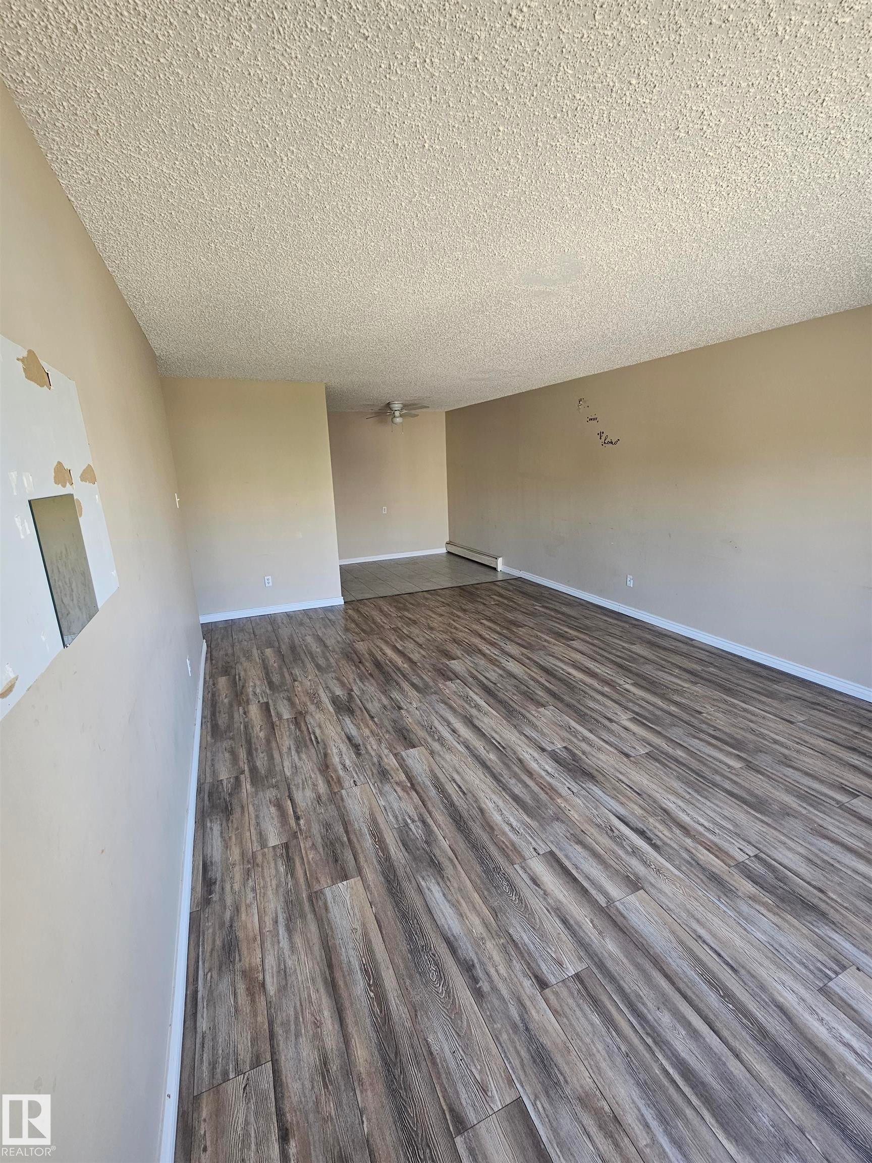 Spacious interior featuring wood-finish flooring, neutral-toned walls, and a textured ceiling - #301 10615 110 Street Nw Nw, Edmonton, AB - Indoor Photo Showing Other Room