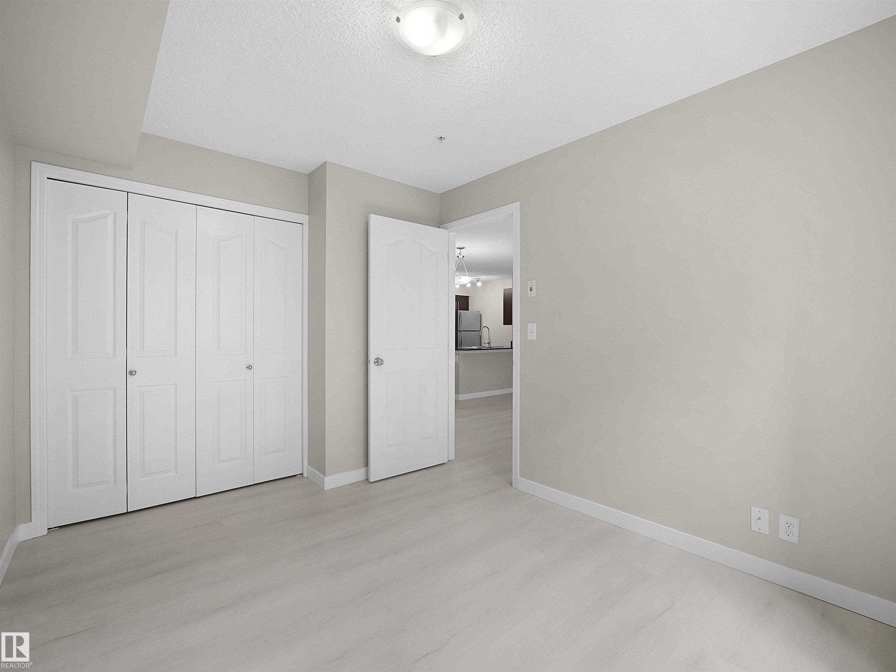 Room featuring light wood-finish flooring and neutral wall tones - 220 12035 22 Avenue, Edmonton, AB