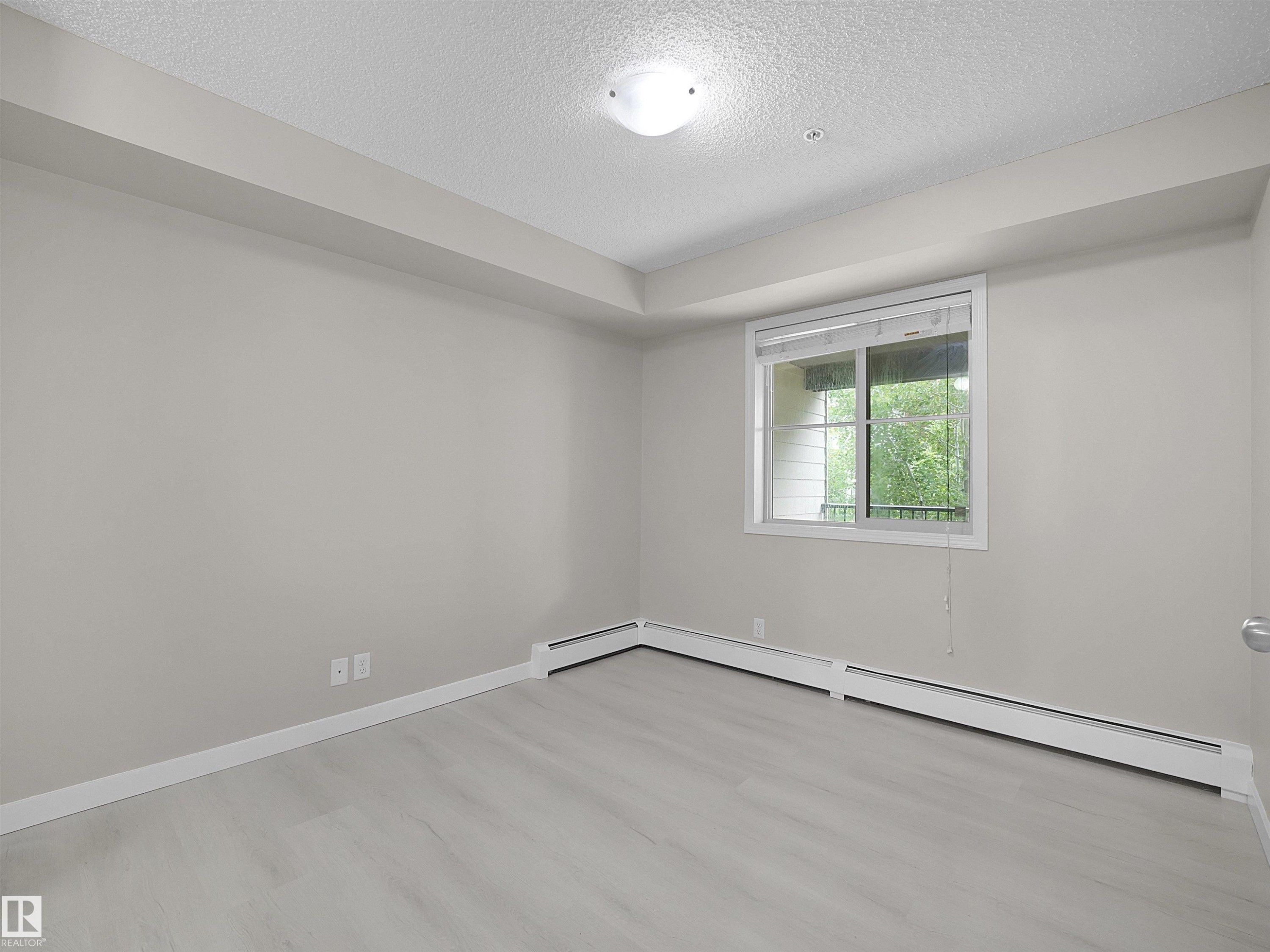 Room featuring light-toned walls and wood-finish flooring - 220 12035 22 Avenue, Edmonton, AB