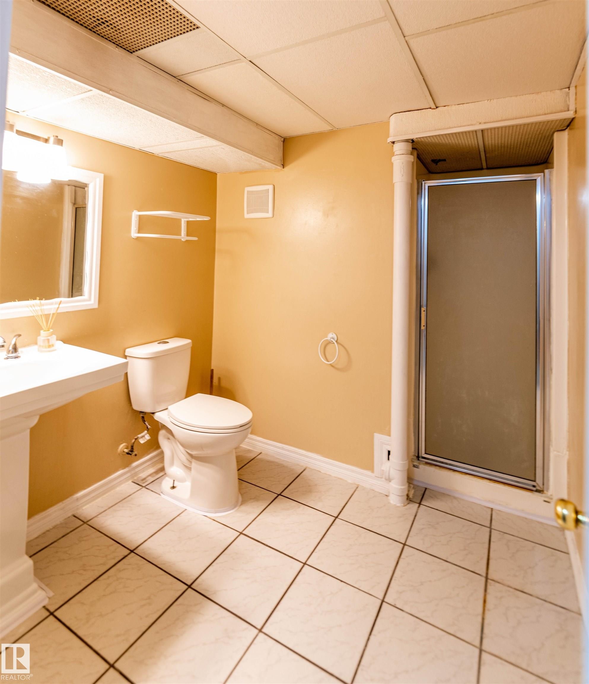 Bathroom featuring a pedestal sink, white toilet, and a glass-enclosed shower - 16524 116 Street, Edmonton, AB