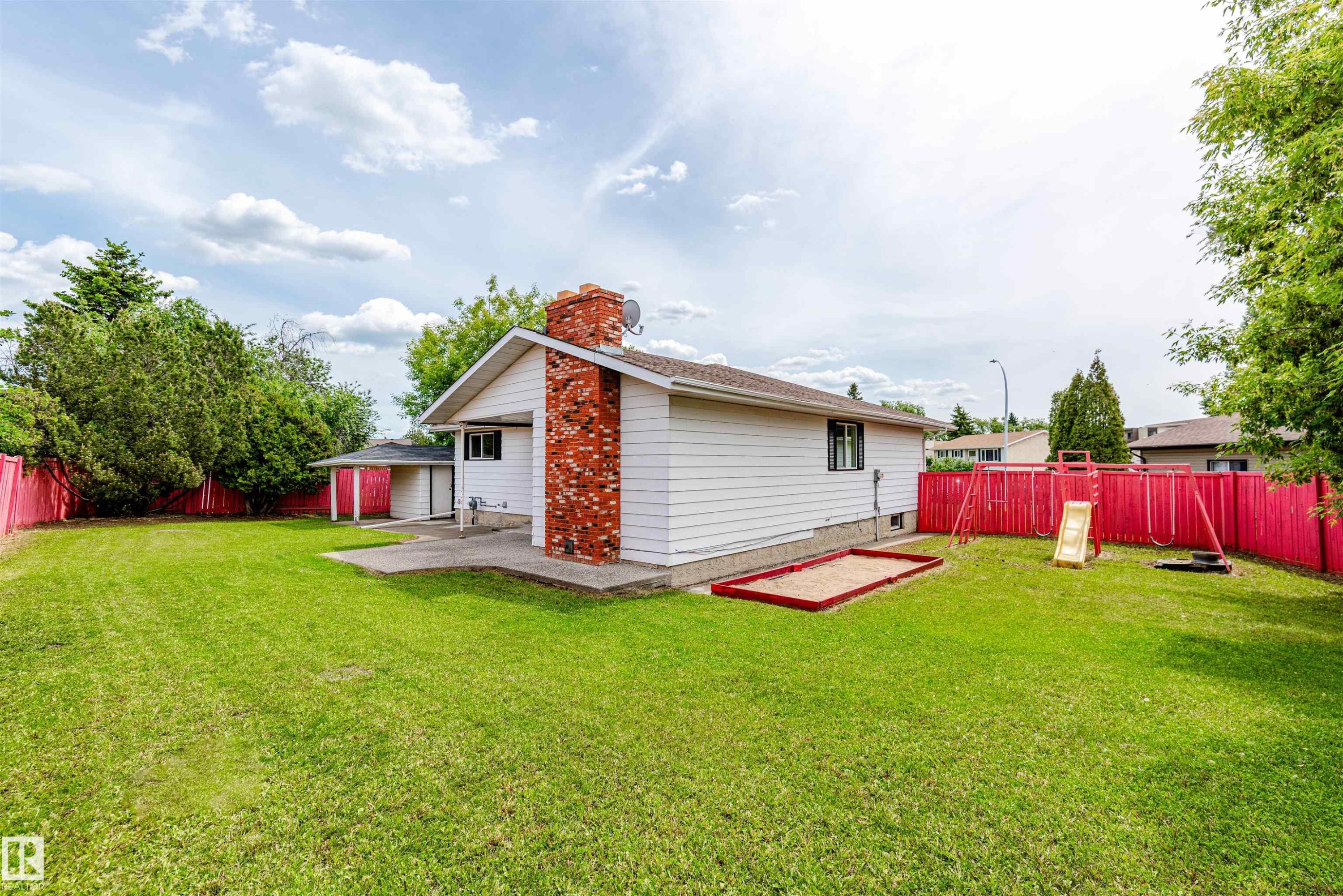 Expansive grassy lawn with a red perimeter fence - 16524 116 Street, Edmonton, AB