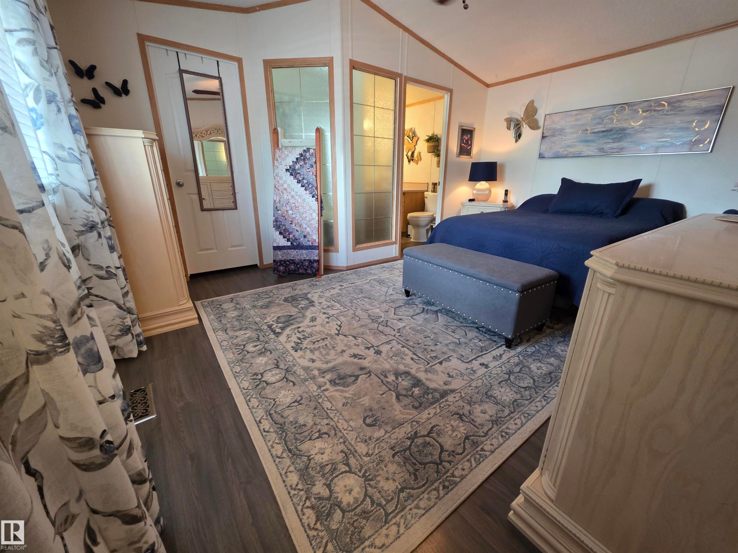 Spacious bedroom featuring wood-finish flooring, a ceiling fan, and decorative wall paneling - 88B 3400 48 Street, Stony Plain, AB
